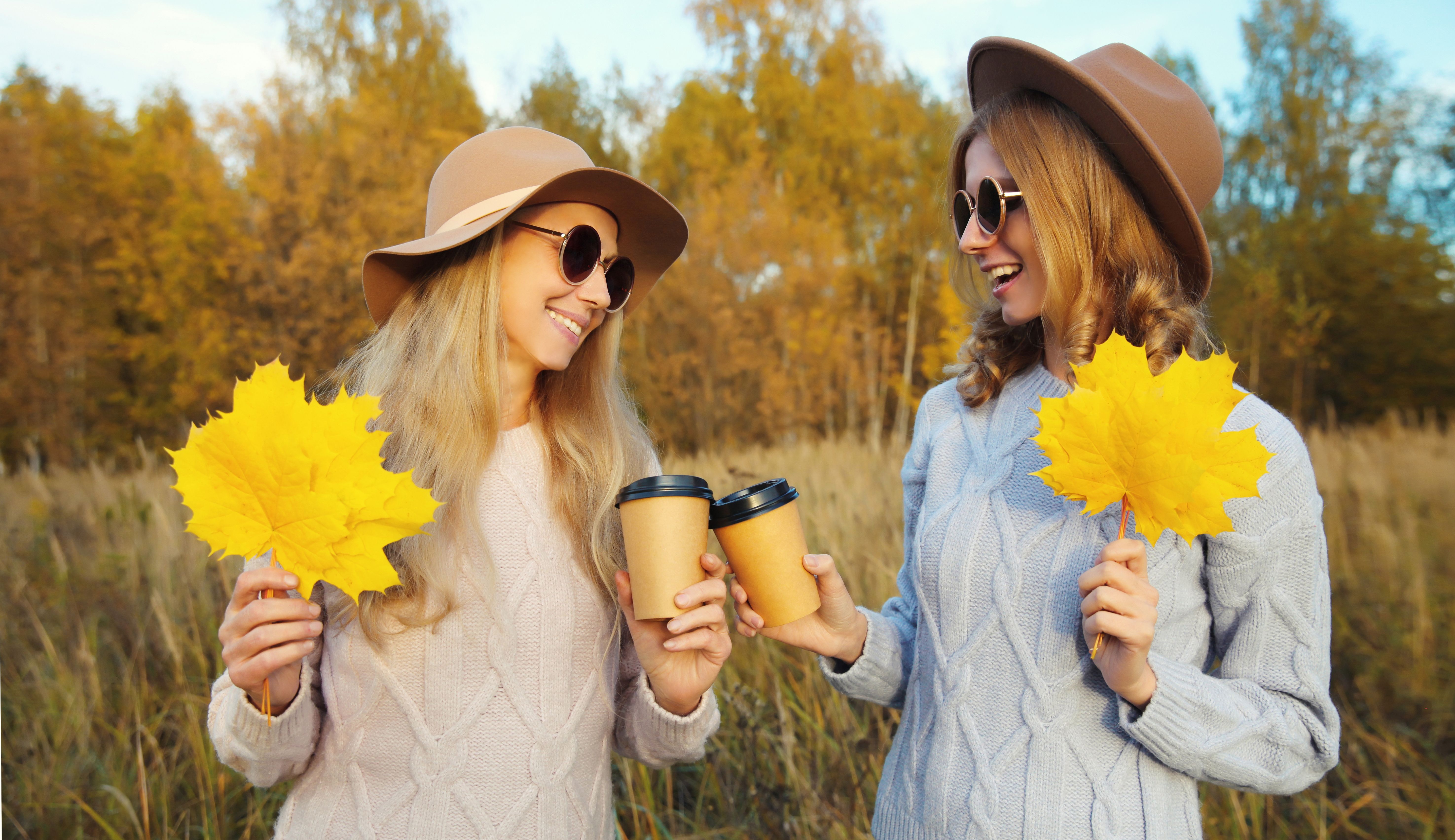 Happy young two women friends with autumn yellow leaves, stylish girlfriends smiles together in park Happy young two women friends with autumn yellow leaves, stylish girlfriends smiles together in park