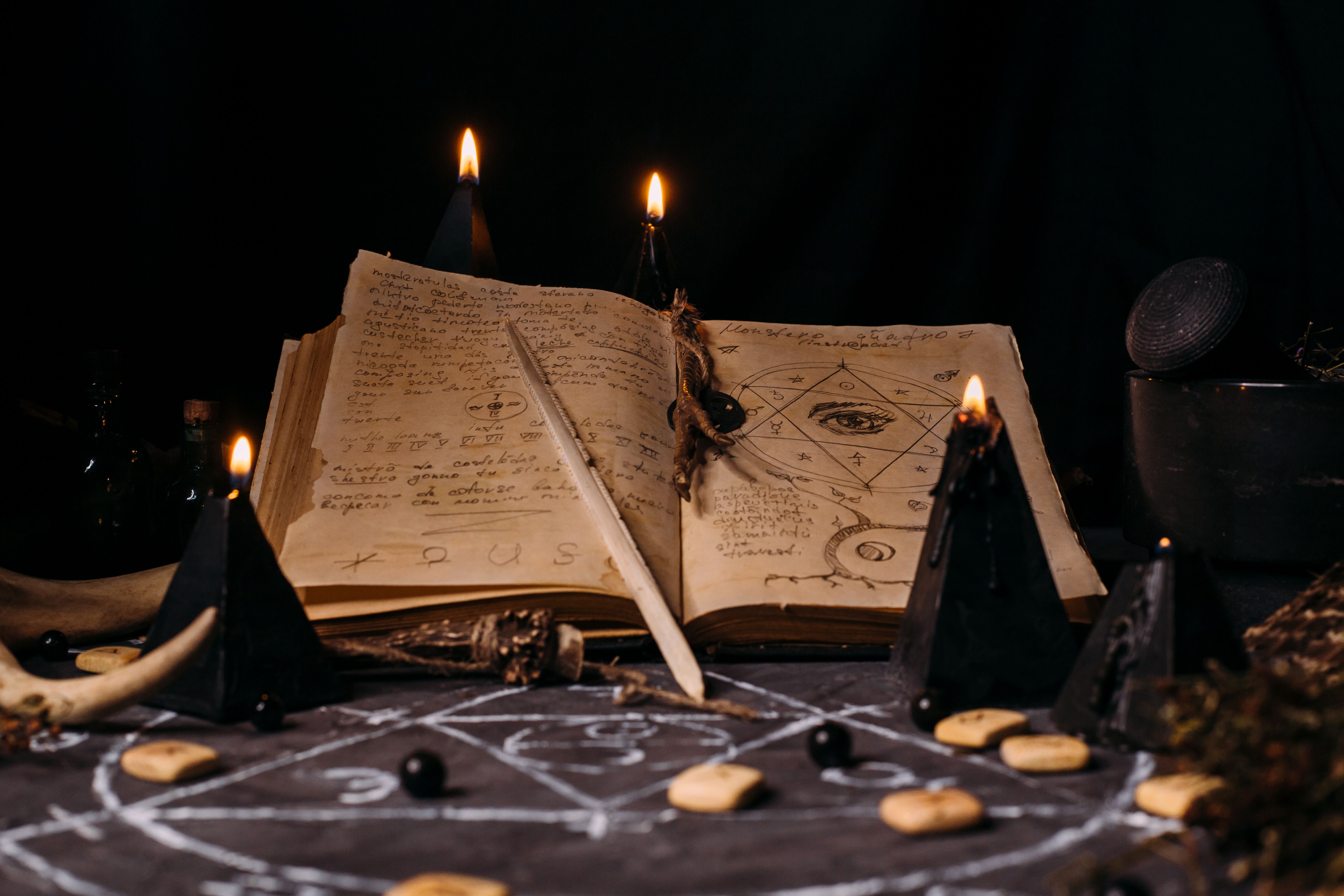 Open old book with magic spells, runes, black candles on witch table. Occult, esoteric, divination and wicca concept. Open old book with magic spells, runes, black candles on witch table. Occult, esoteric, divination and wicca concept.
