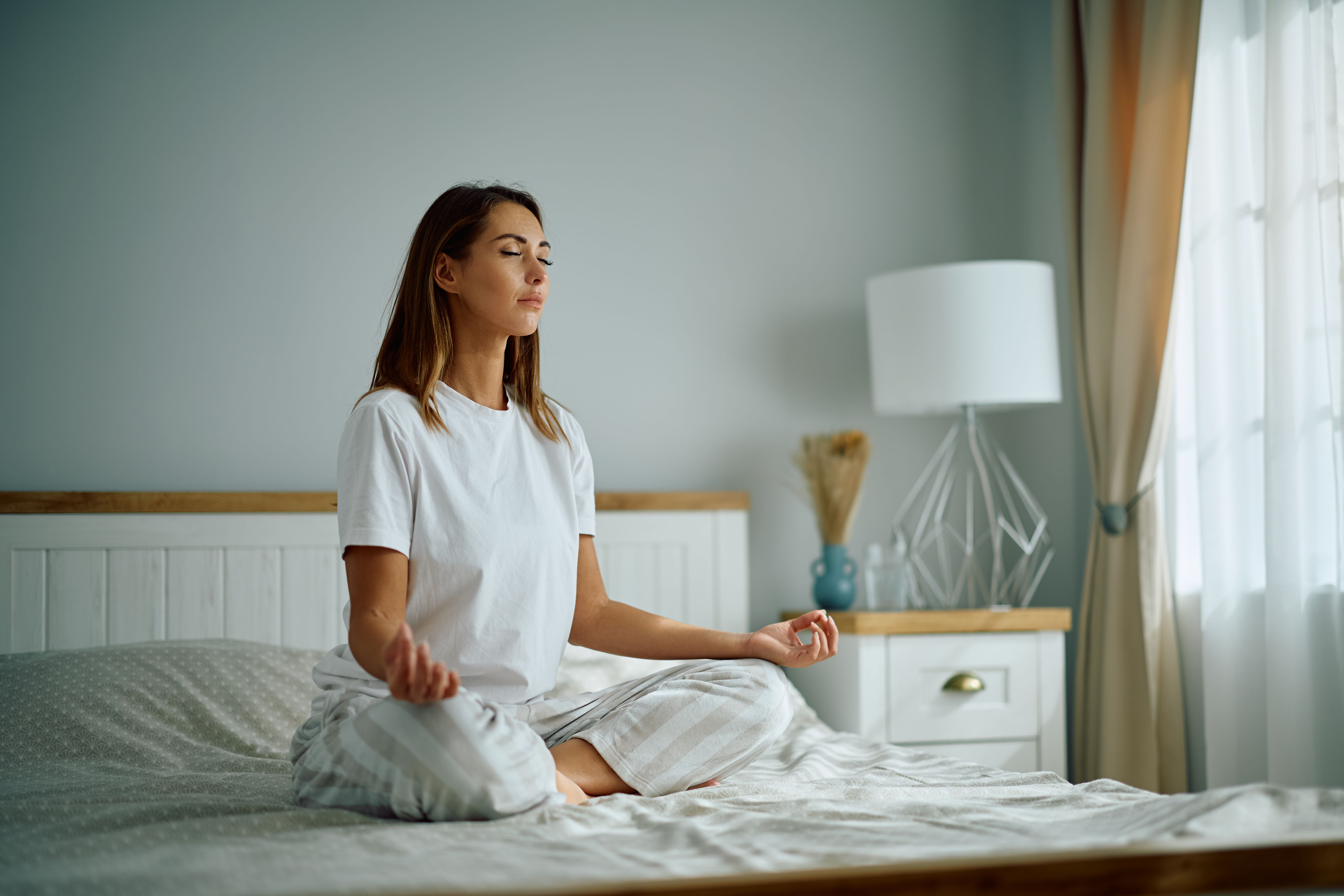 Young woman with eyes closed doing Yoga breathing exercise in the morning.
