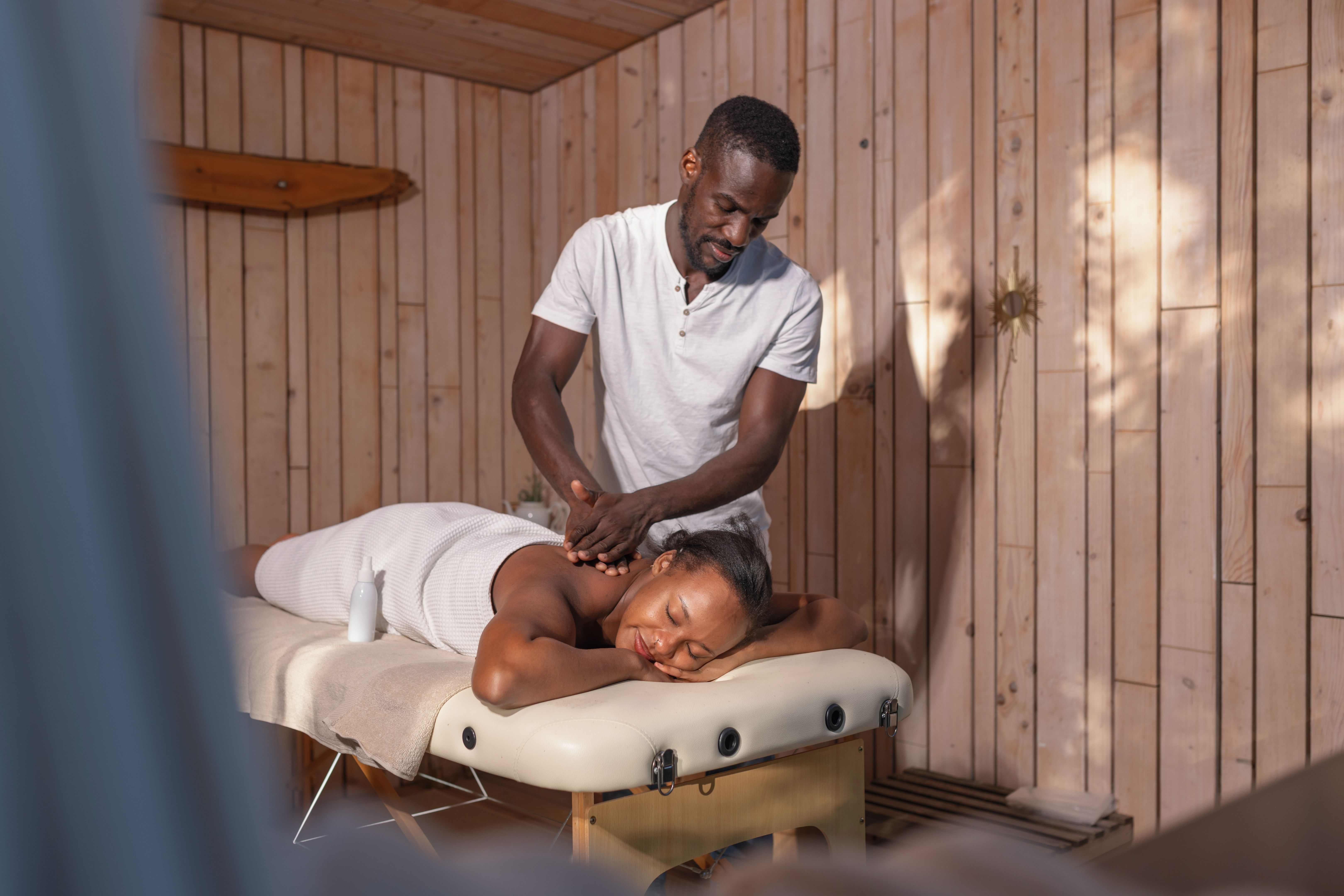 African American woman with closed eyes relaxing in a spa while getting a massage