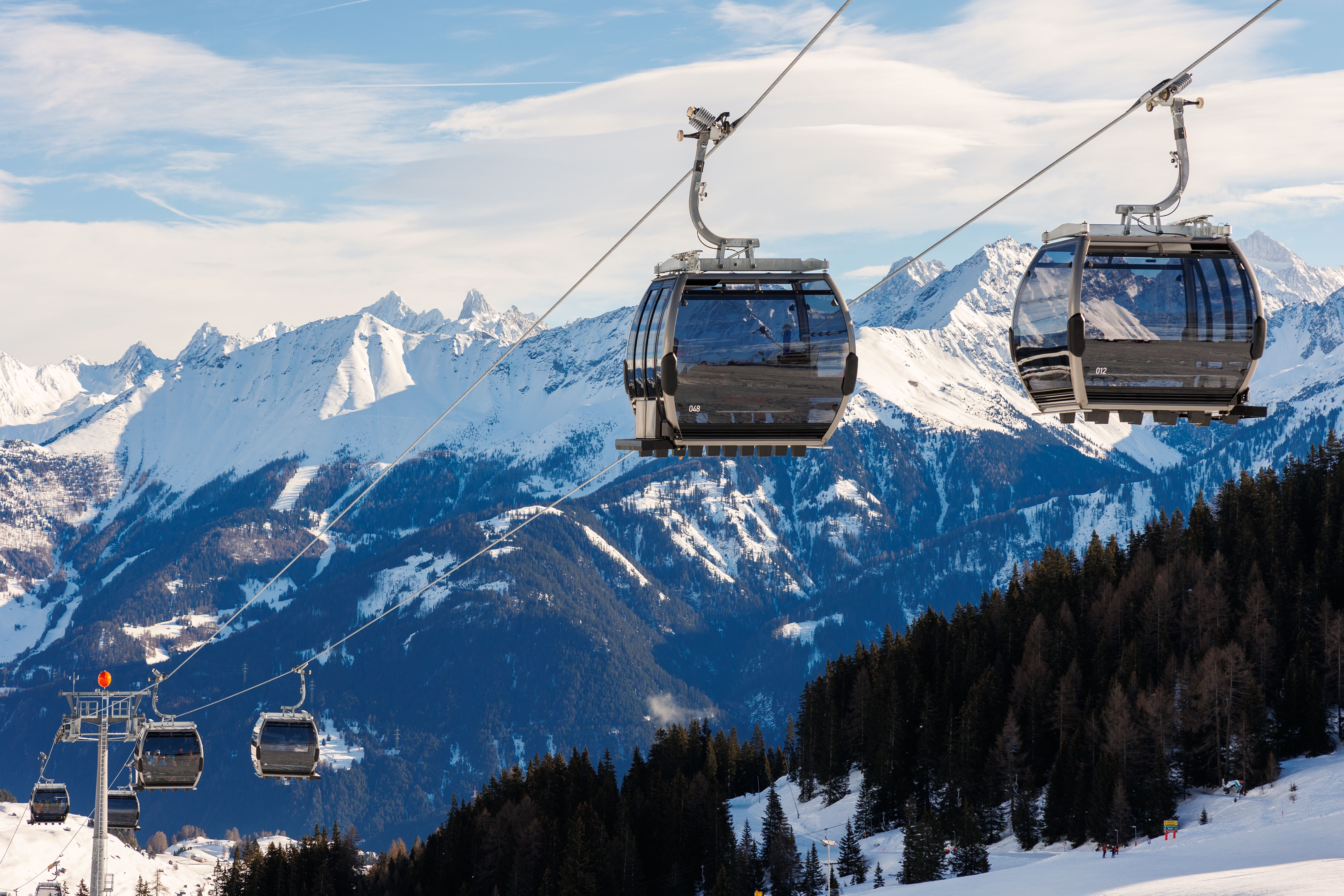 New modern spacious big cabin ski lift gondola against snowcapped forest tree and mountain peaks covered in snow landscape in luxury winter alpine resort. Winter leisure sports, recreation and travel