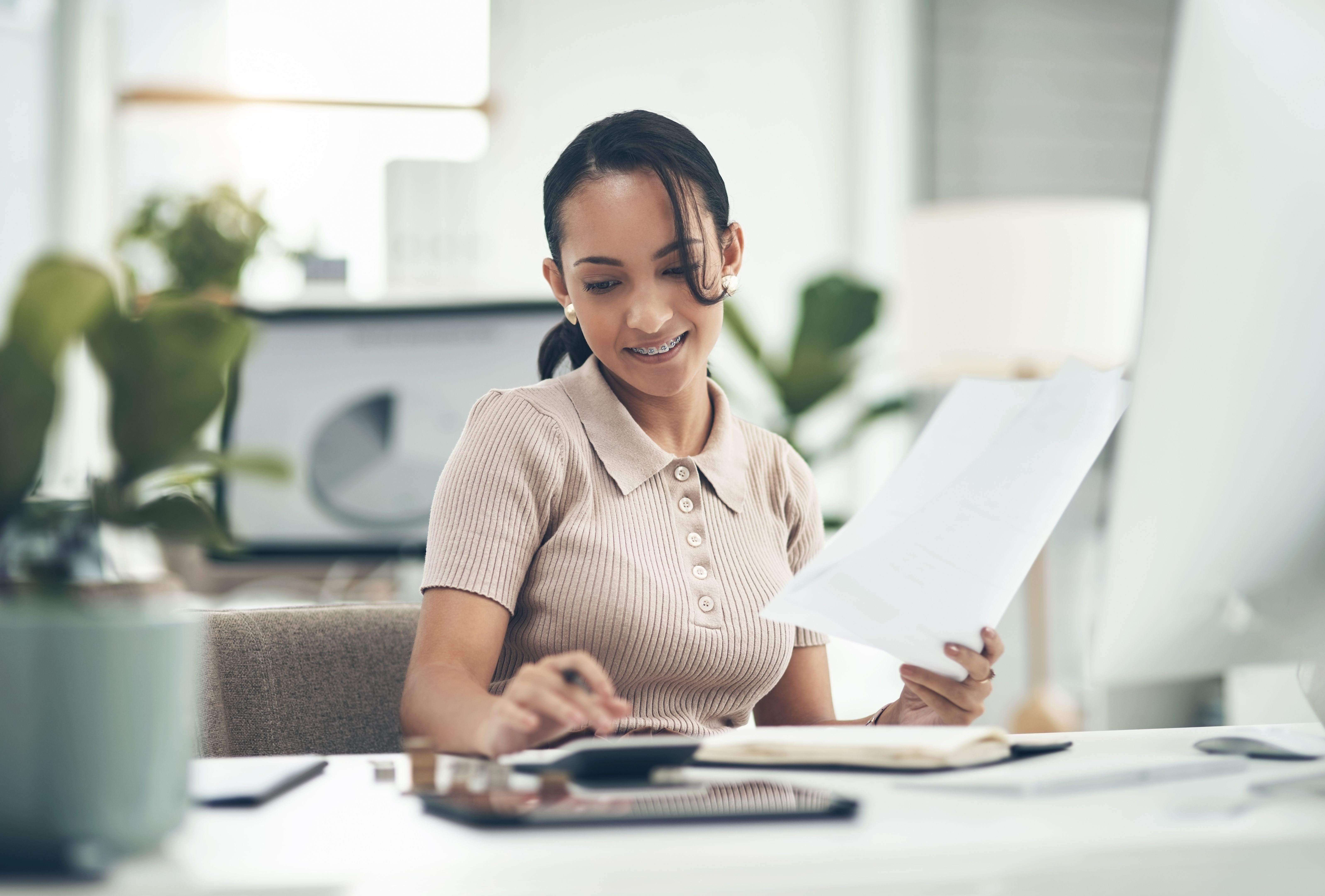 Shot of a young businesswoman calculating finances in an office