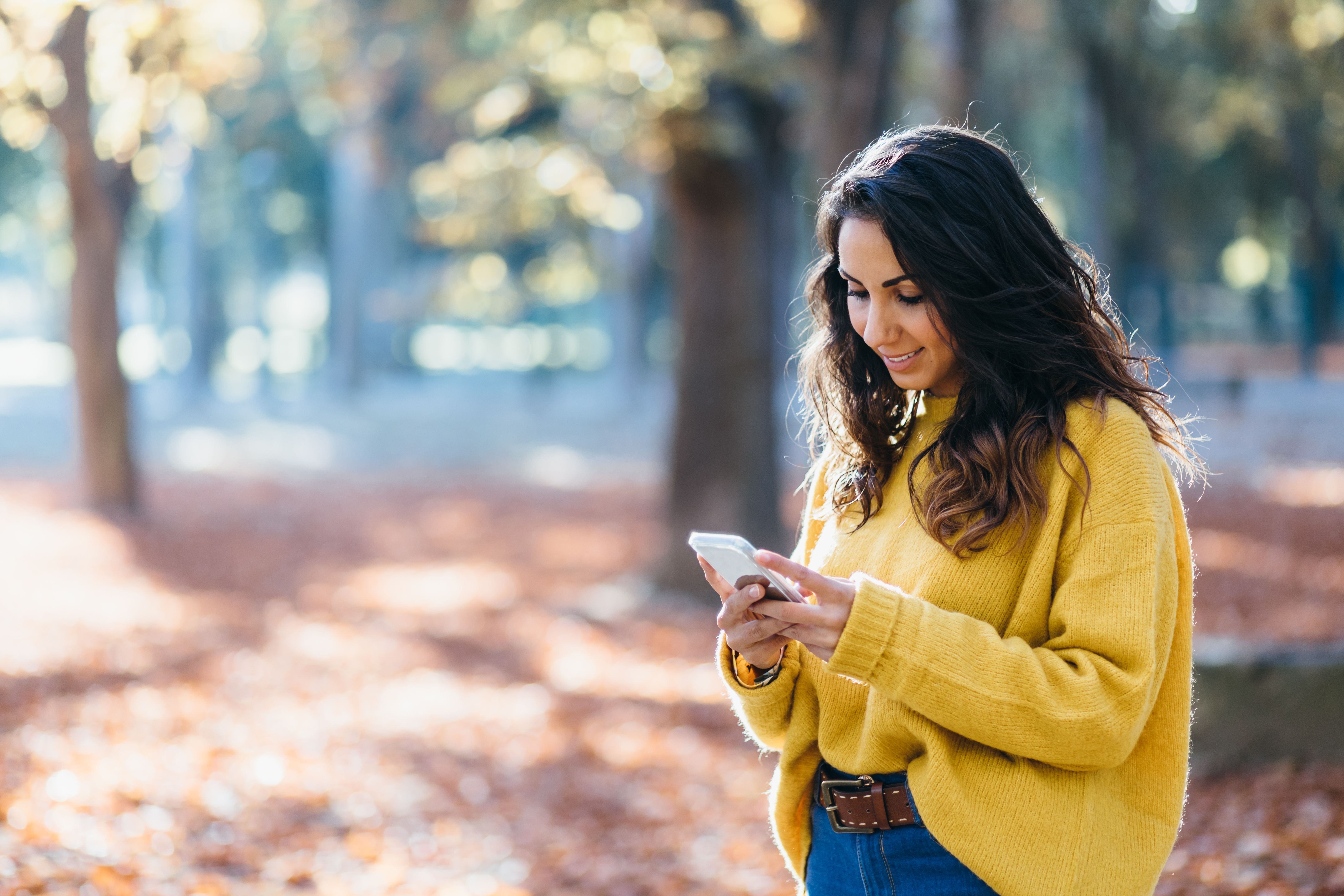 Casual woman messaging on smartphone in autumn