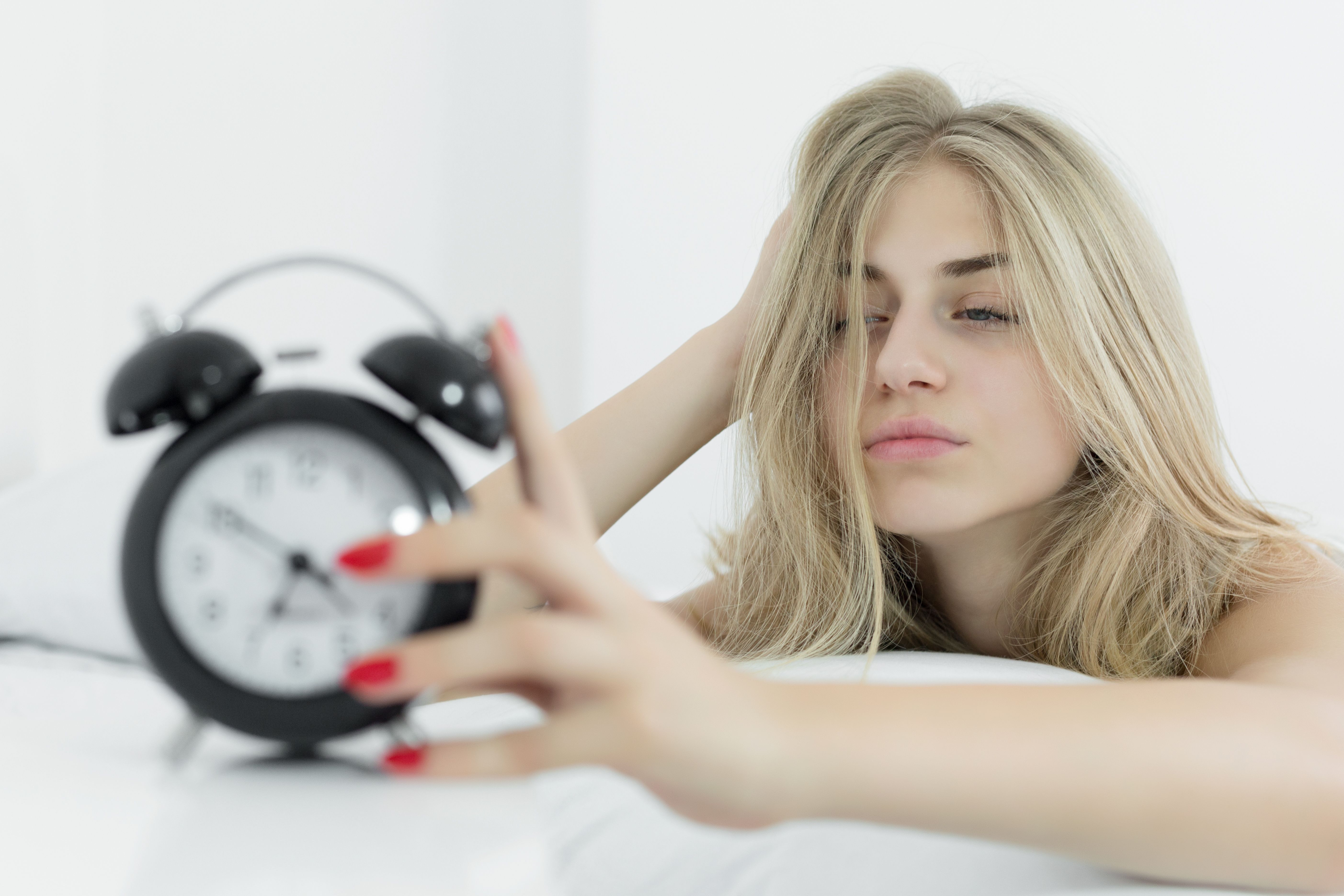 Woman in bed holding alarm clock