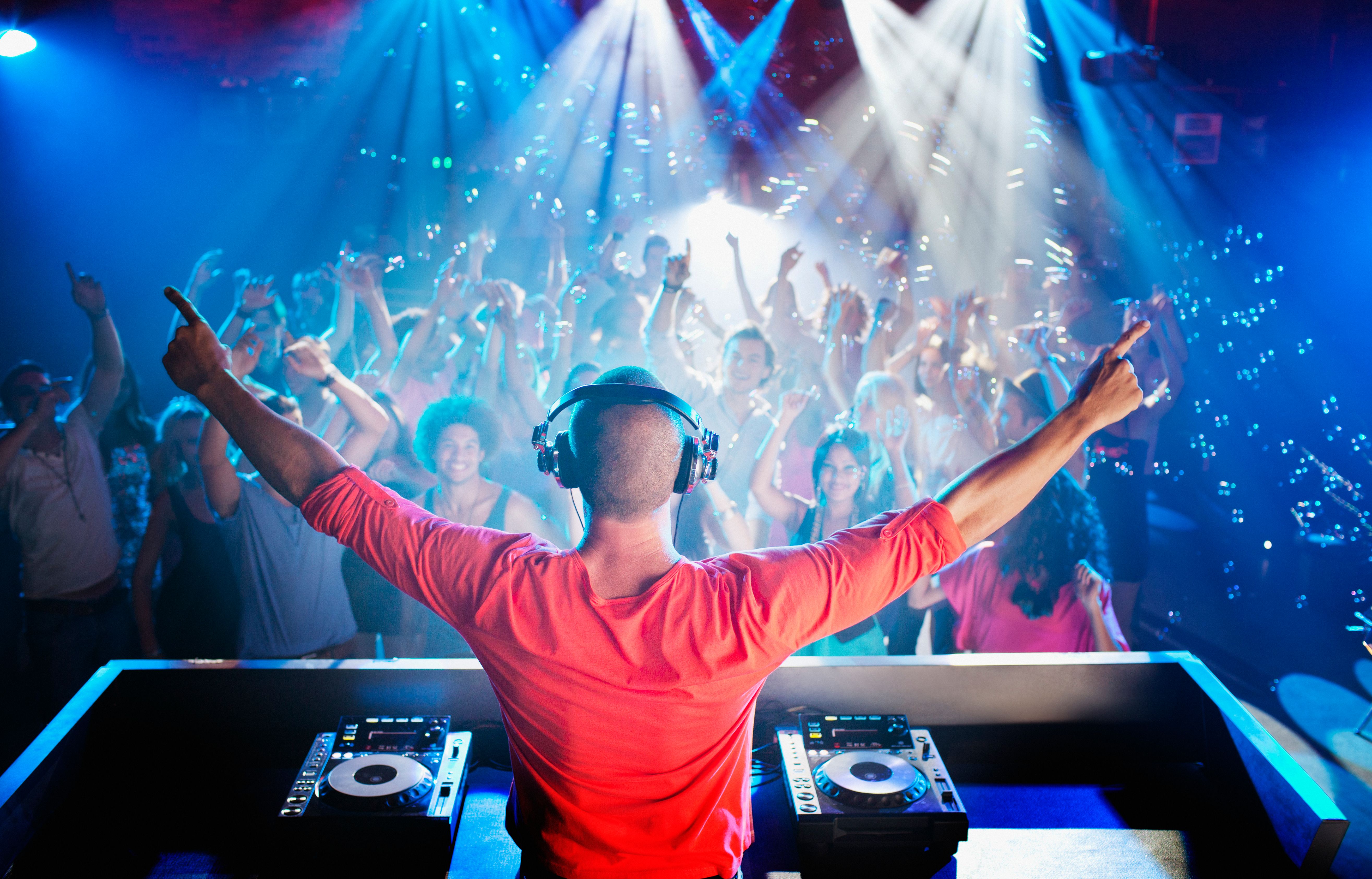 DJ with arms outstretched overlooking dance floor DJ with arms outstretched overlooking dance floor