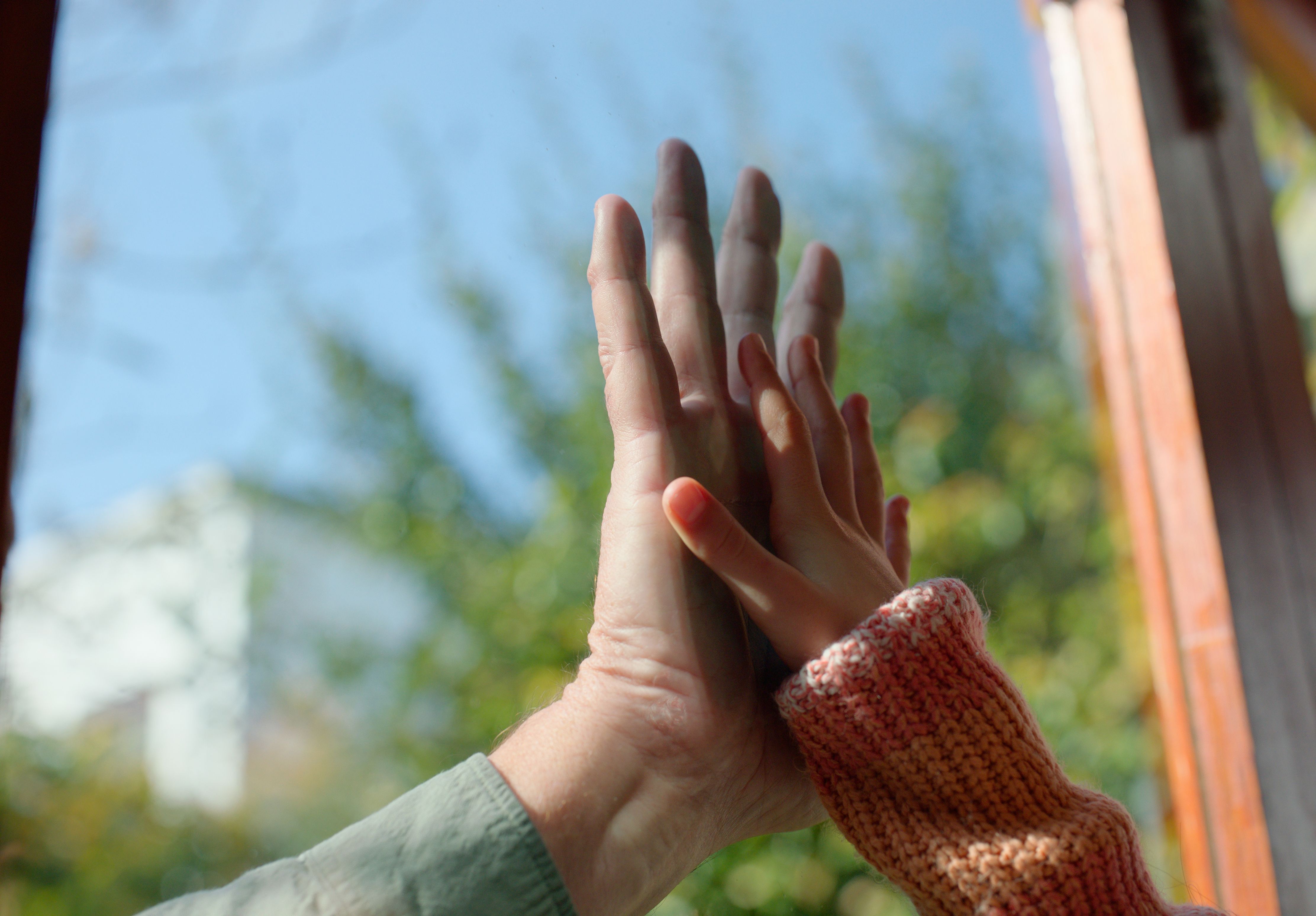 Familie, Hände und Berührung mit Trennung durch Fenster in der Wohnung für Sorgerecht, Sozialarbeit oder Kinderschutzdienst. Eltern, Kind und Handfläche für Verbindung, Sicherheit oder Schutz vor Gefahren mit Glas im Haus