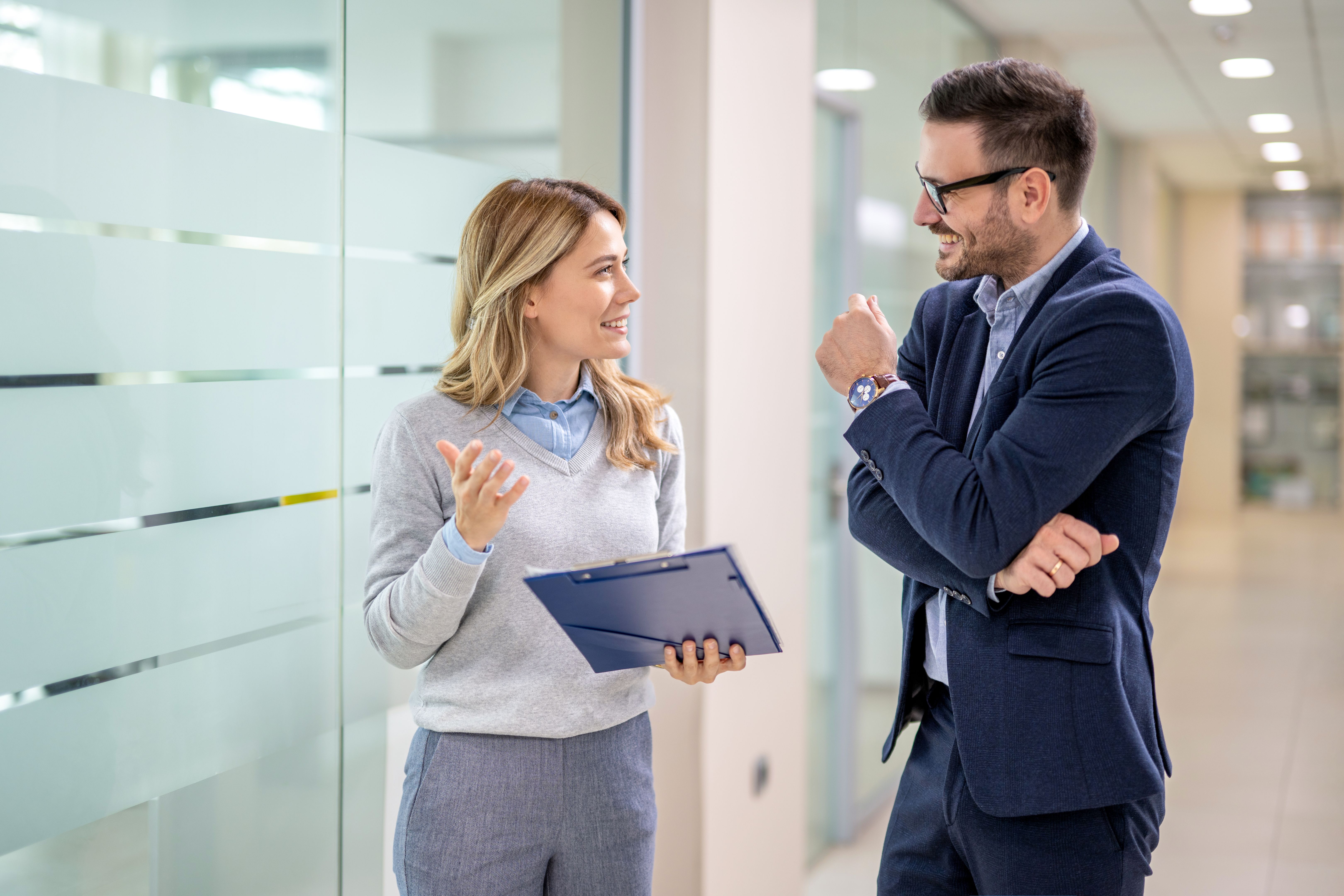 Portrait of beautiful blonde business woman having informal meeting with handsome man in formal-wear at office hall.
