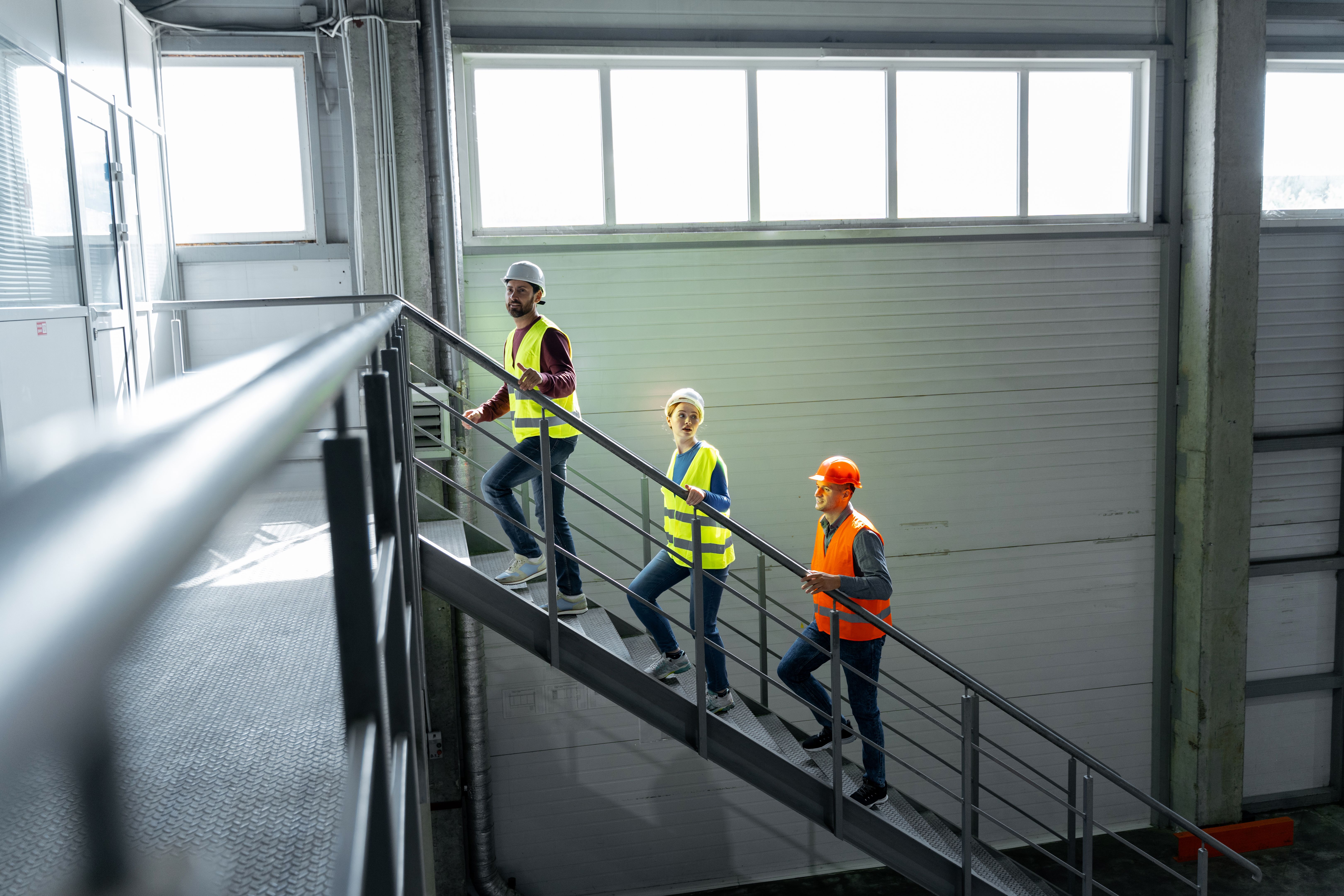 Group of successful factory workers, managers wearing hard hats, vests and work wear walking Group of successful factory workers, managers wearing hard hats, vests and work wear walking