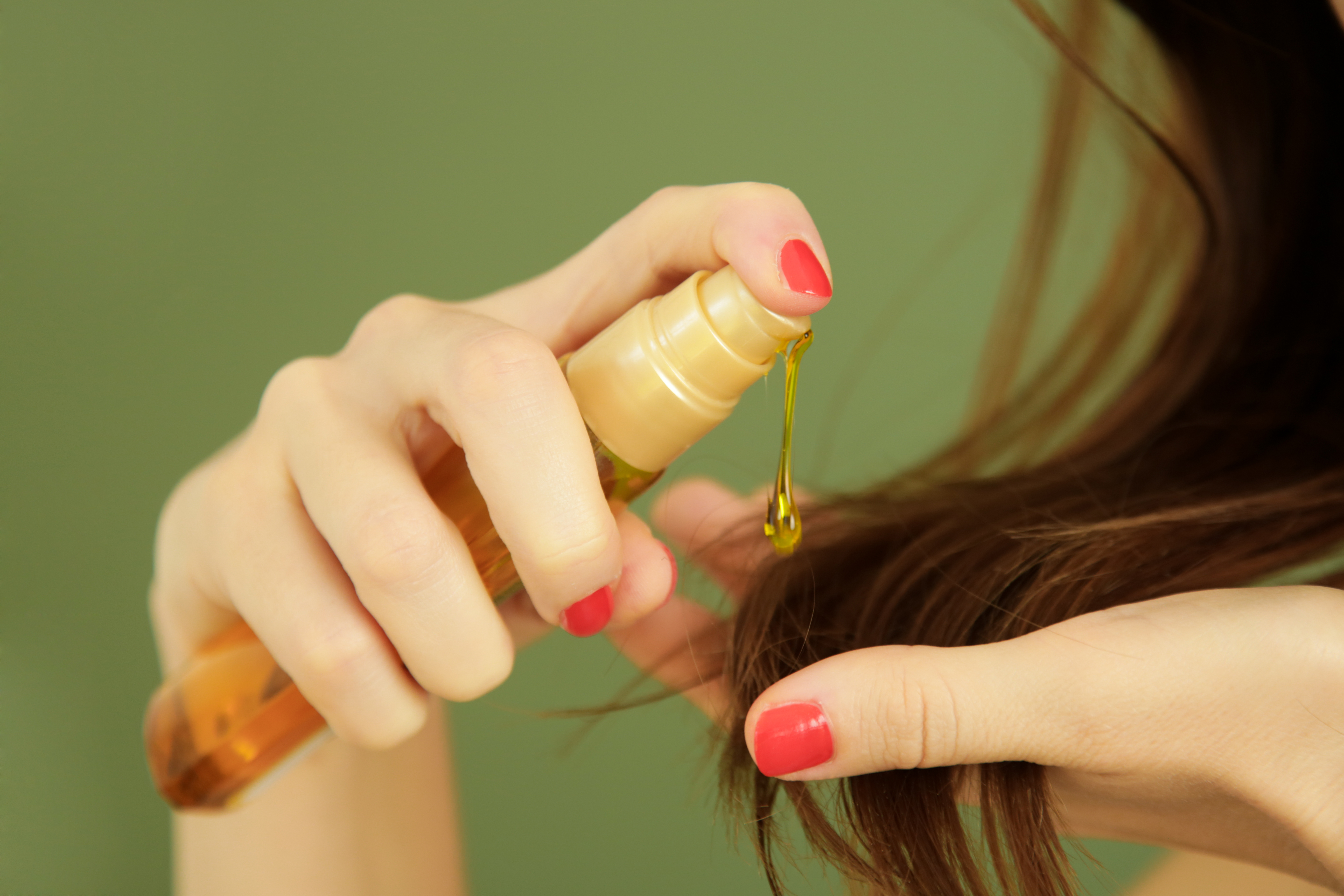 Woman applying oil on hair ends, split hair tips, dry hair or sun protection concept Woman applying oil on hair ends, split hair tips, dry hair or sun protection concept