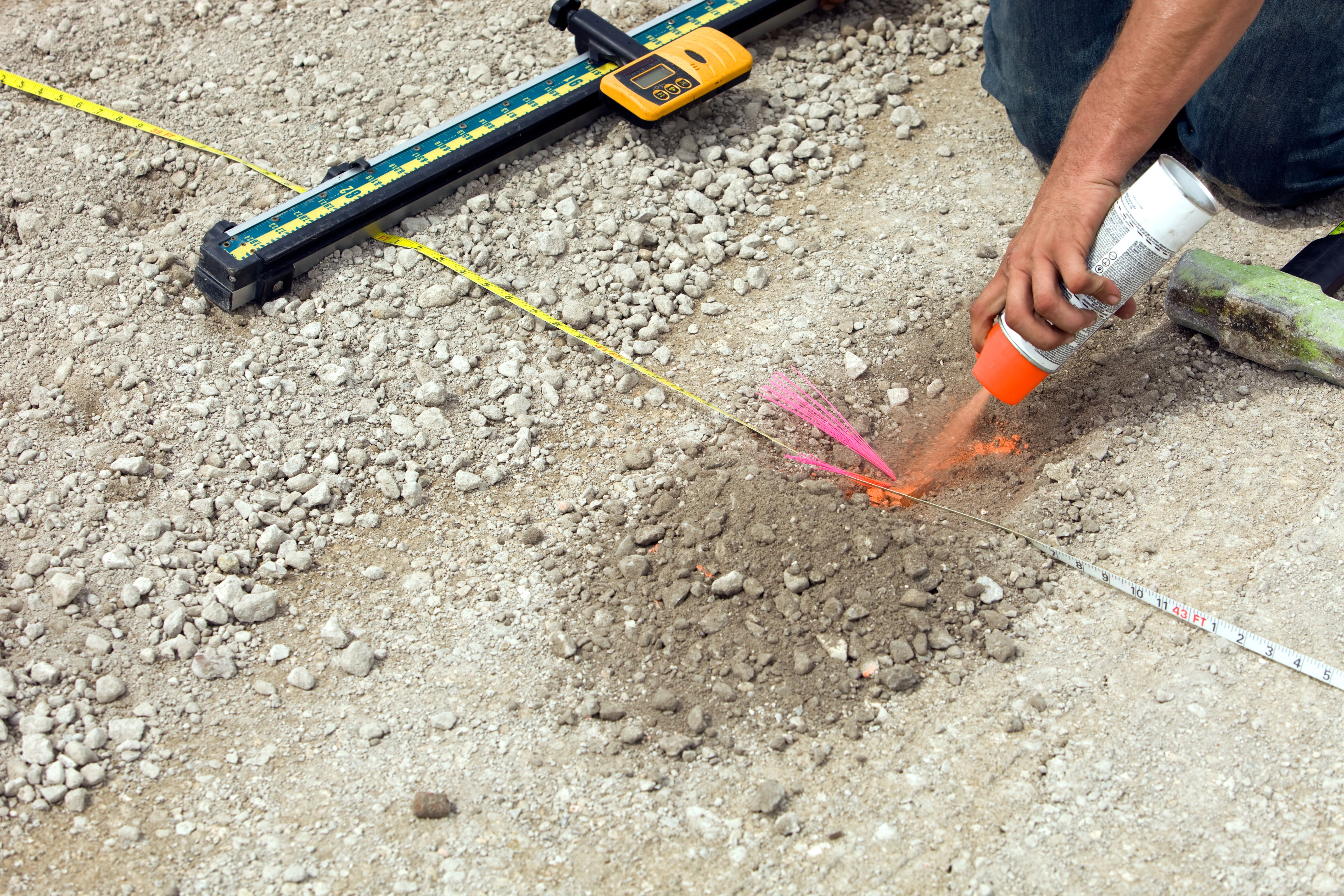 Land Surveyor Marks Grade Point on a Parking Lot Site