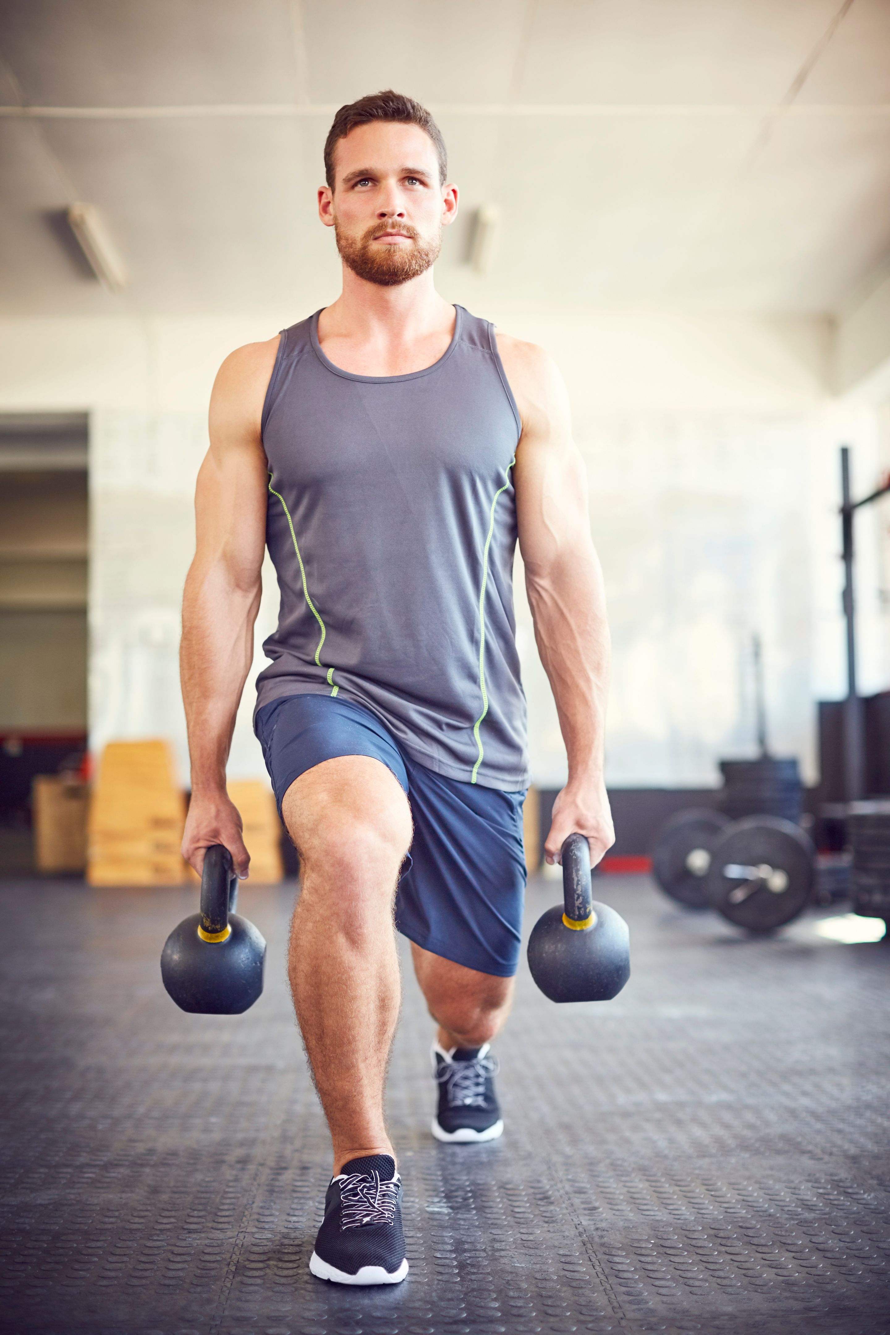 Determined male athlete lifting kettlebells in gym