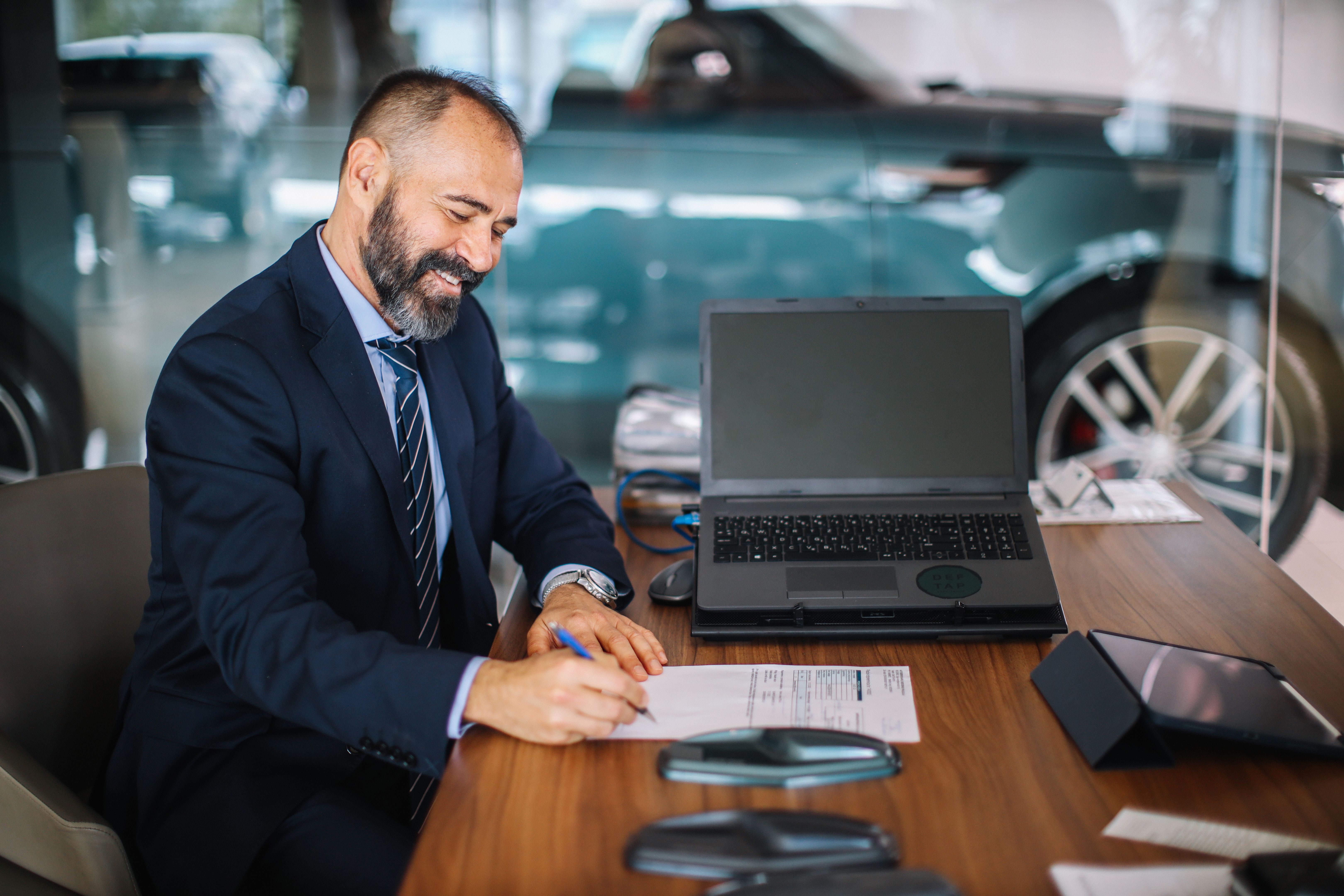 Homem de meia idade assinando a papelada do carro no showroom