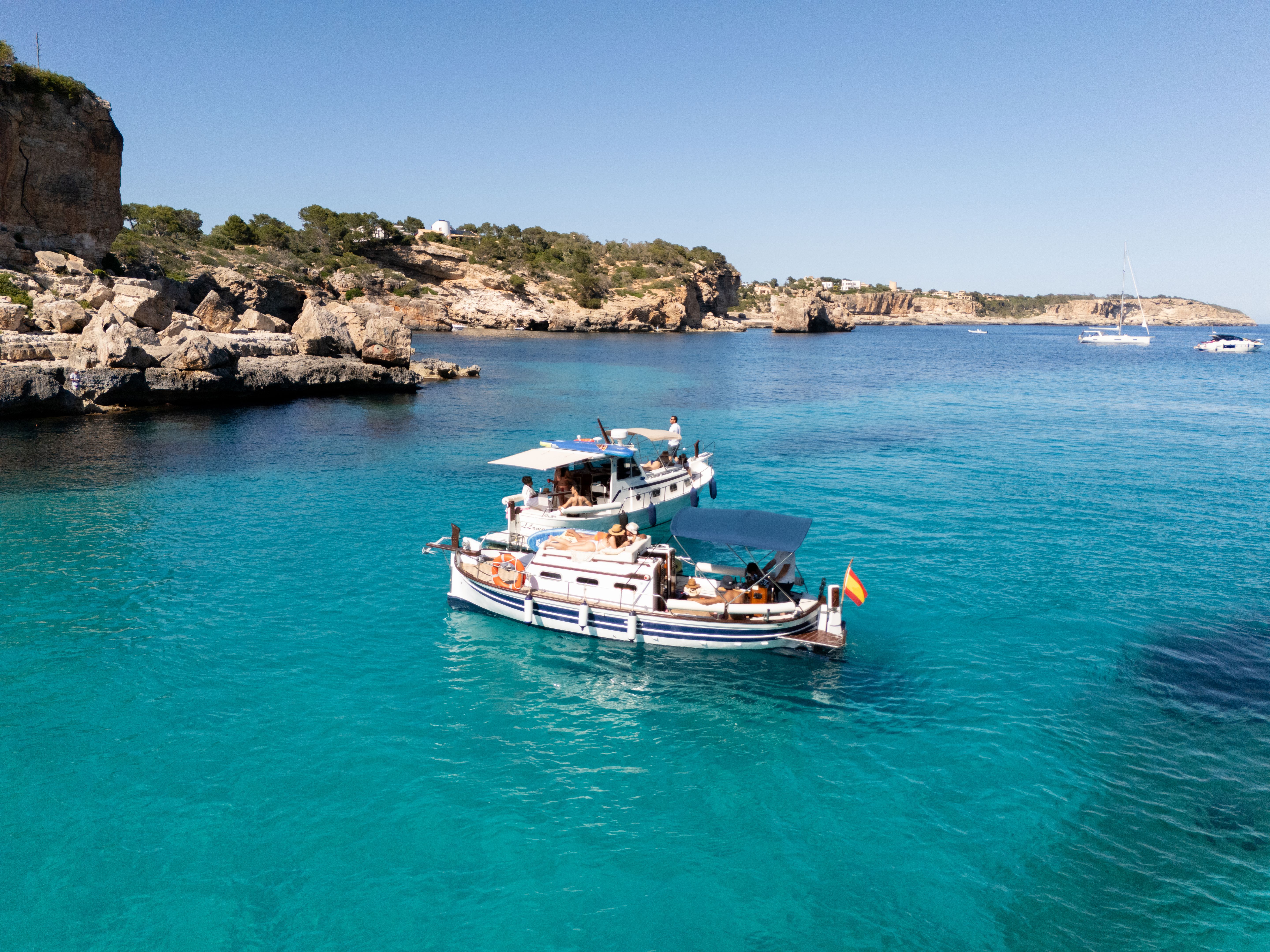 People relaxing on traditional boats anchored in turquoise bay