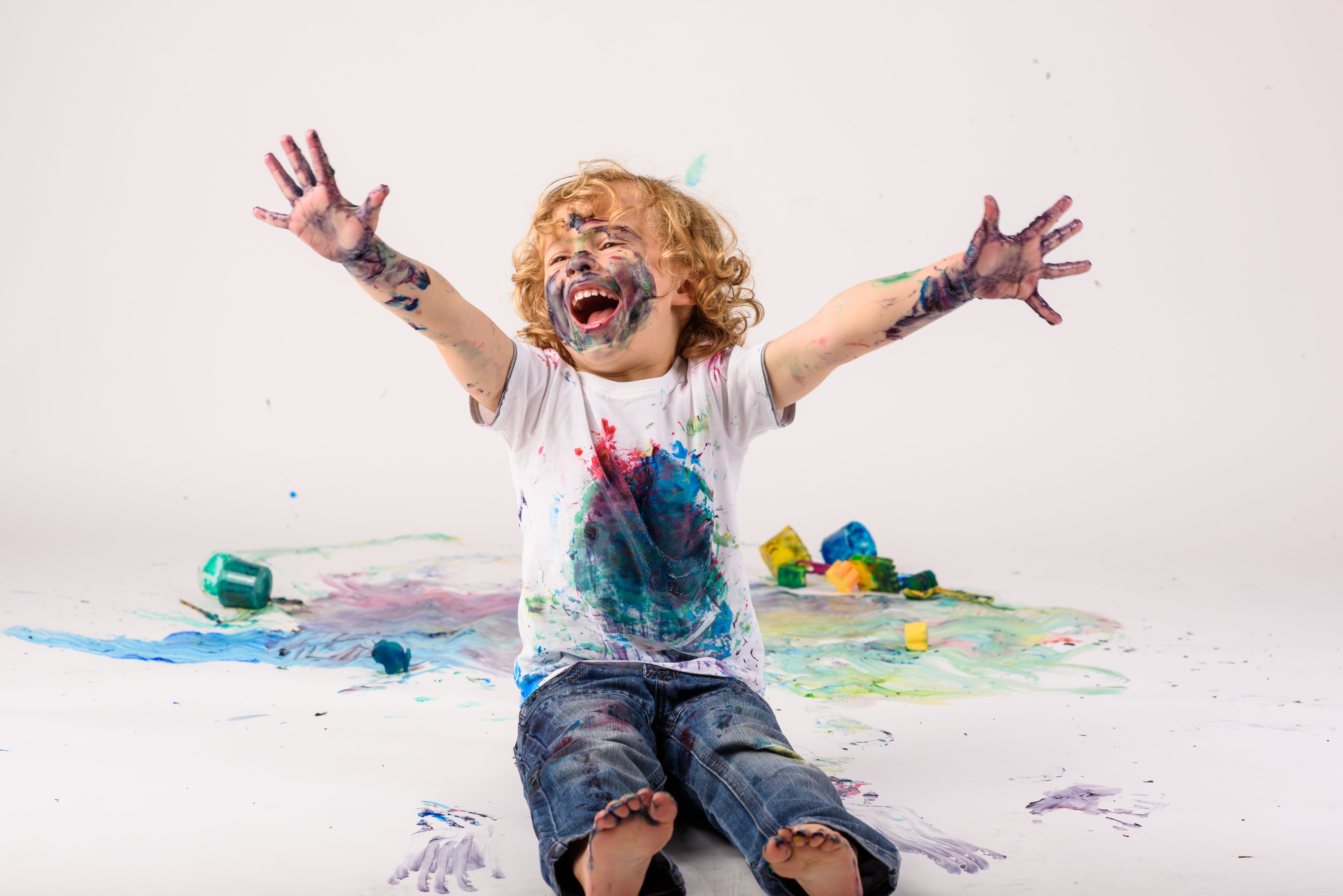 Excited boy covered with paints in studio