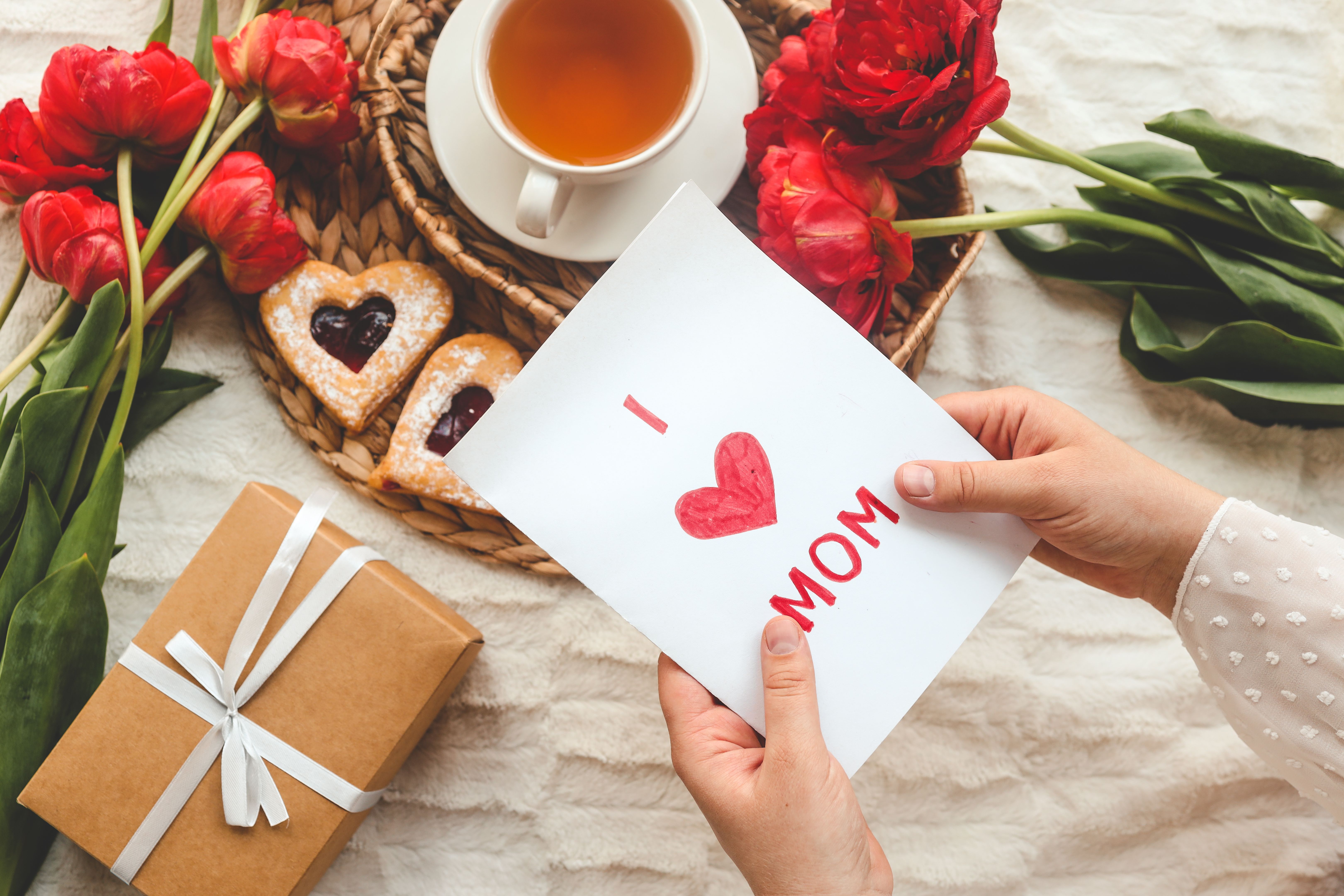 Woman hands holding a beautiful hand drawn Mother's Day greeting card with red envelope, I Love You Mom message on the card Woman hands holding a beautiful hand drawn Mother's Day greeting card with red envelope, I Love You Mom message on the card