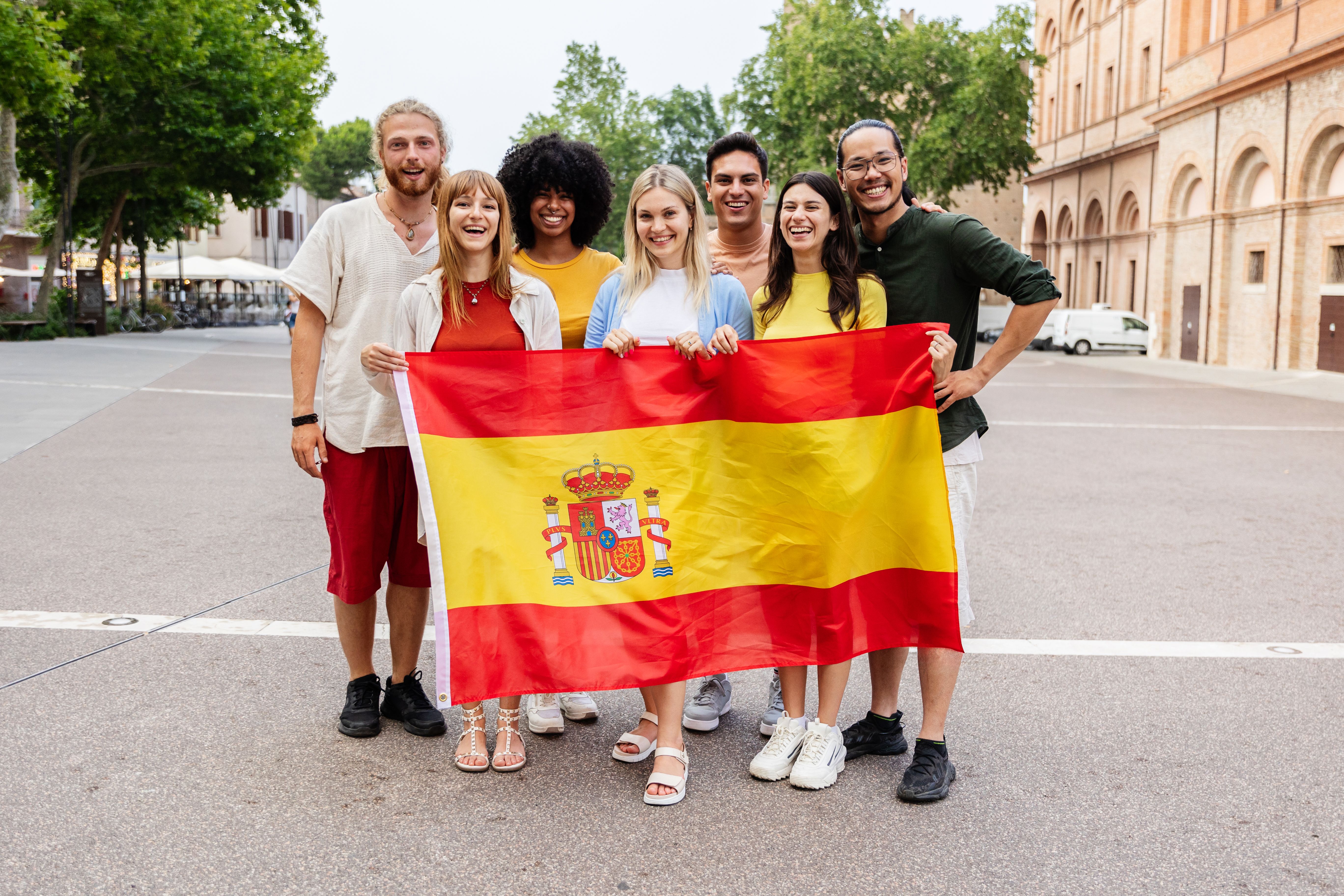 Diverse group of people looking at the camera holding spanish flag outdoors