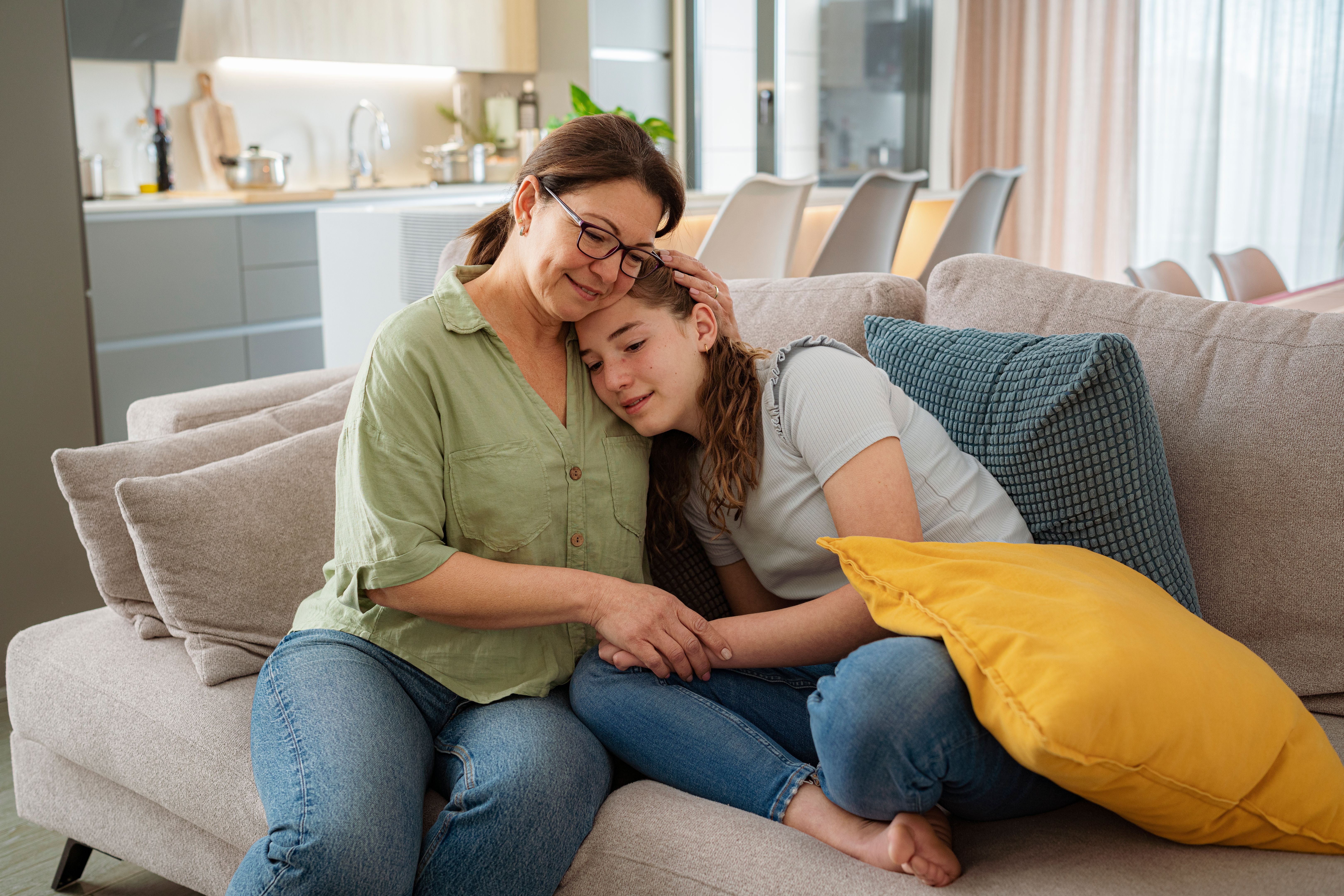 Loving mother and teenager daughter hugging on the sofa