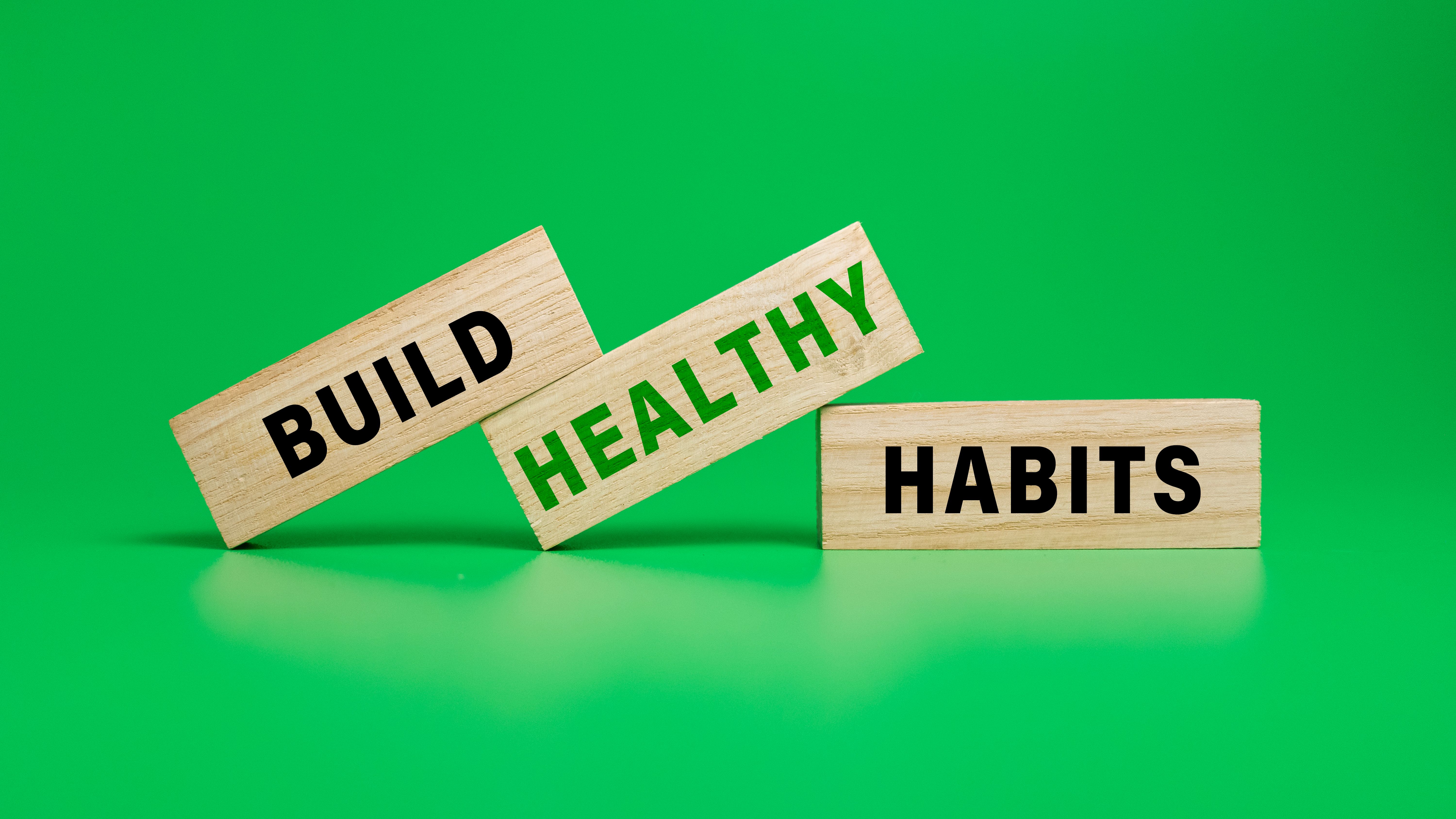 build healthy habits on wooden blocks isolated on green background