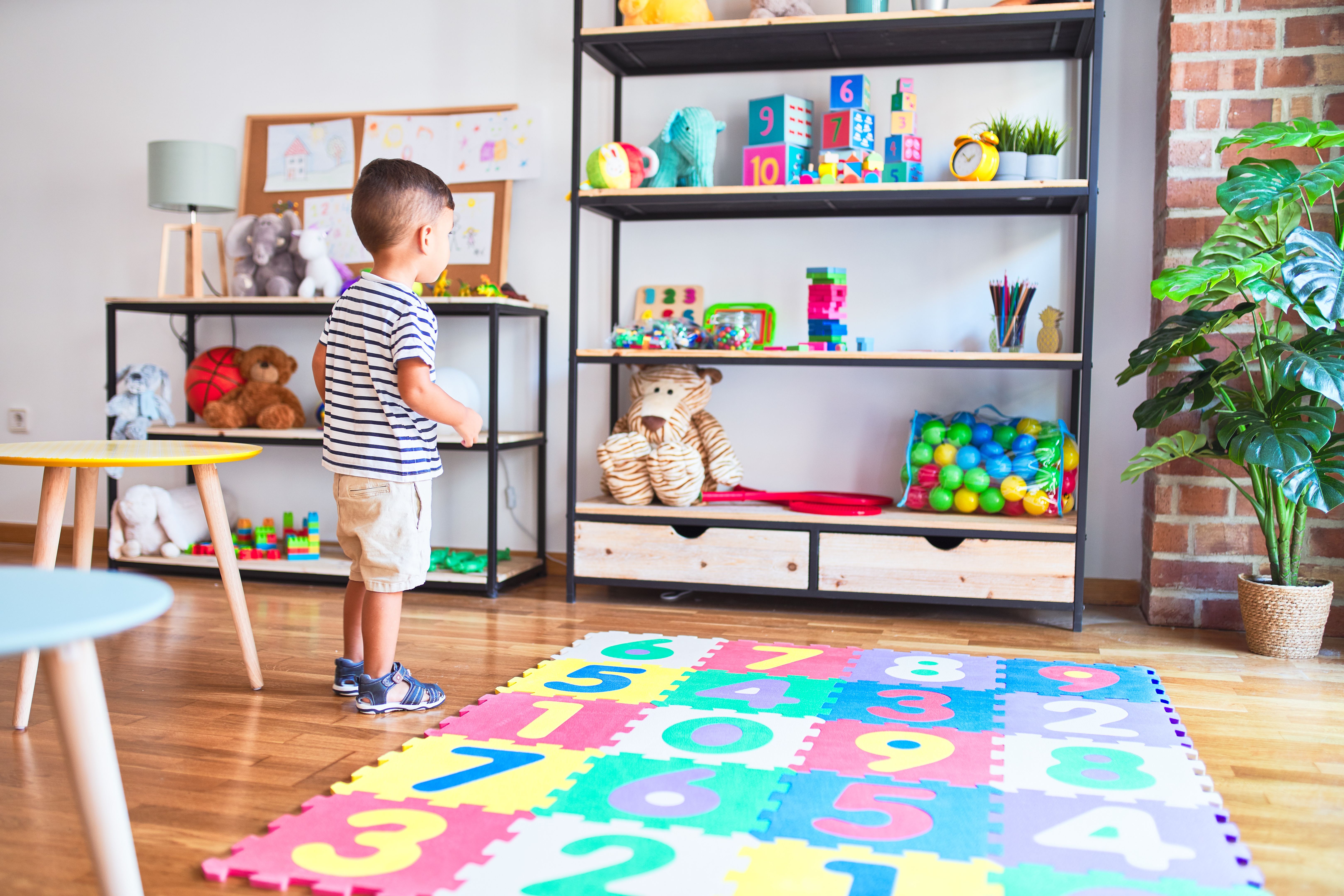 Beautiful toddler boy holding magnifying glass at kindergarten