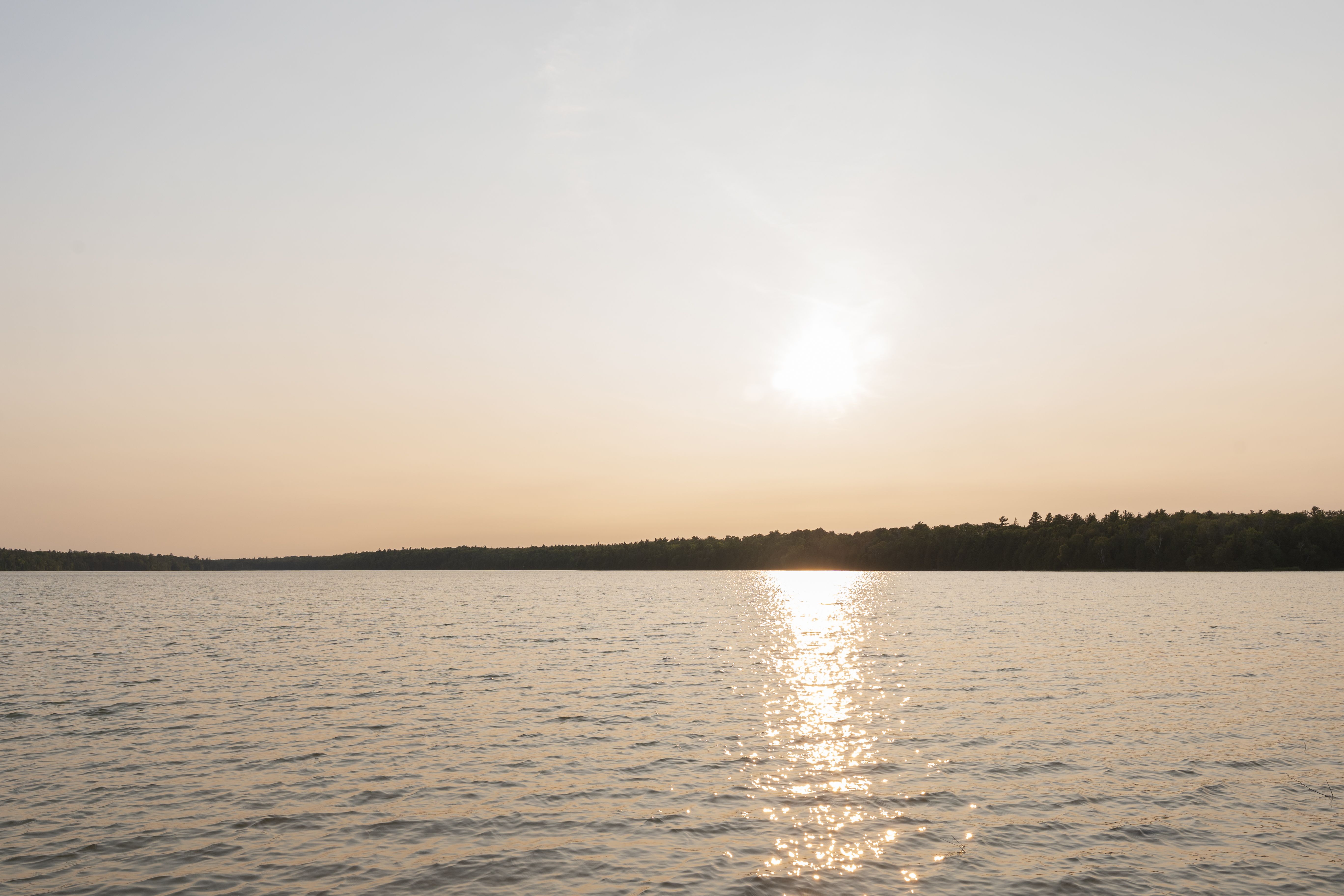 Breathtaking golden hour over a tranquil lake, with warm sunlight reflecting on the calm water.