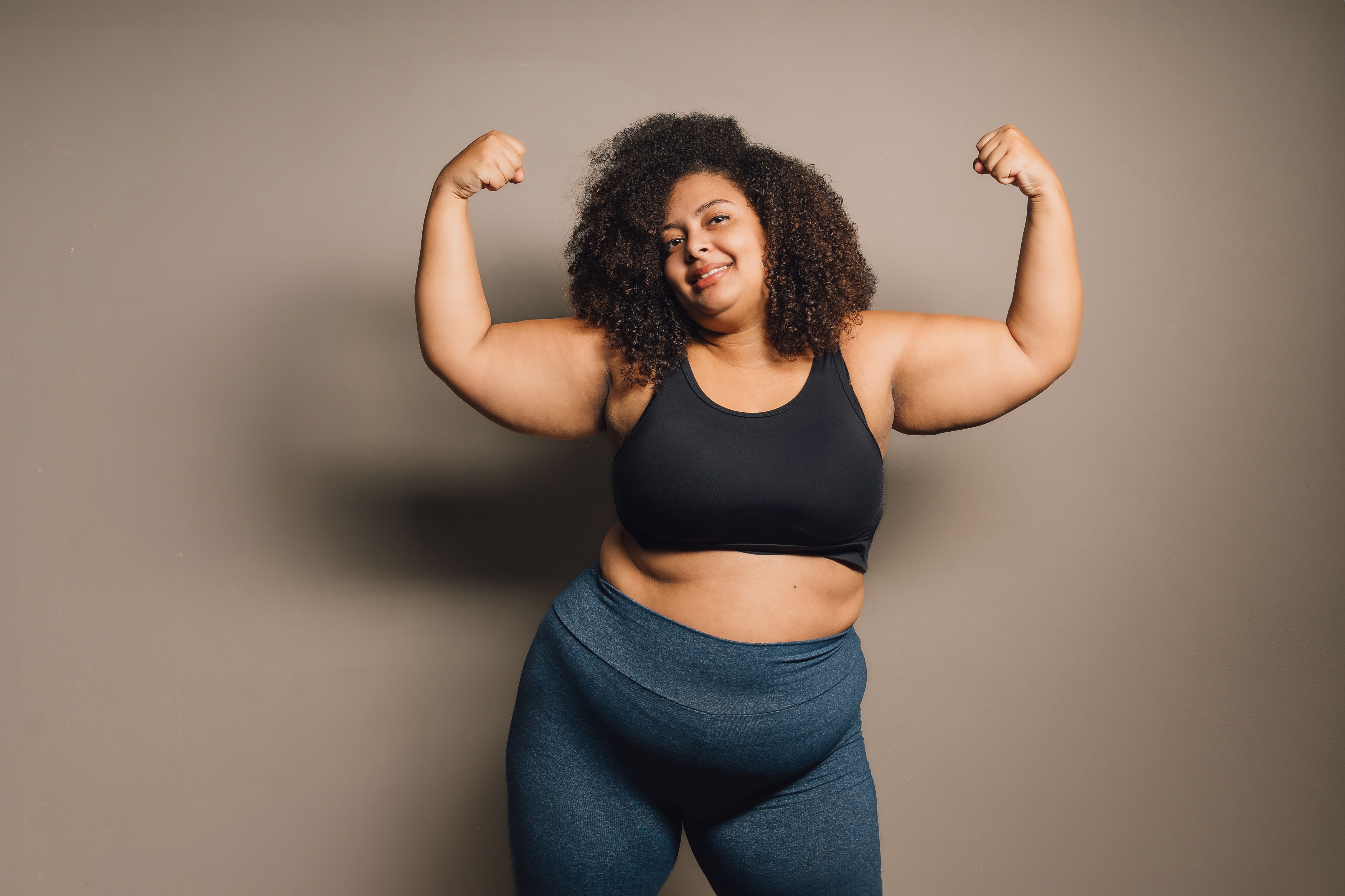 Portrait of a plus size woman showing biceps - vitality concept