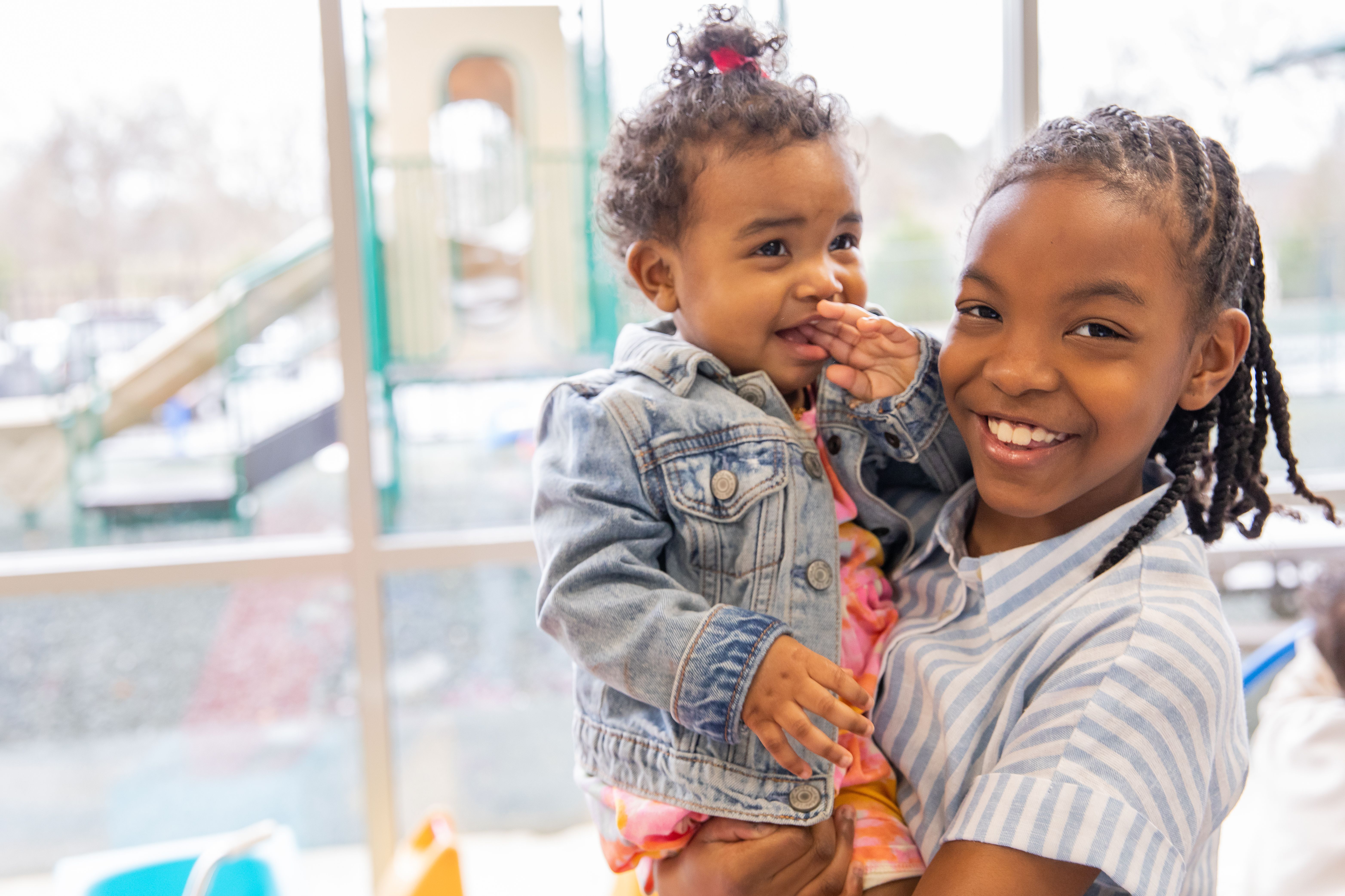 Little girl  holds her toddler sister at a childcare center