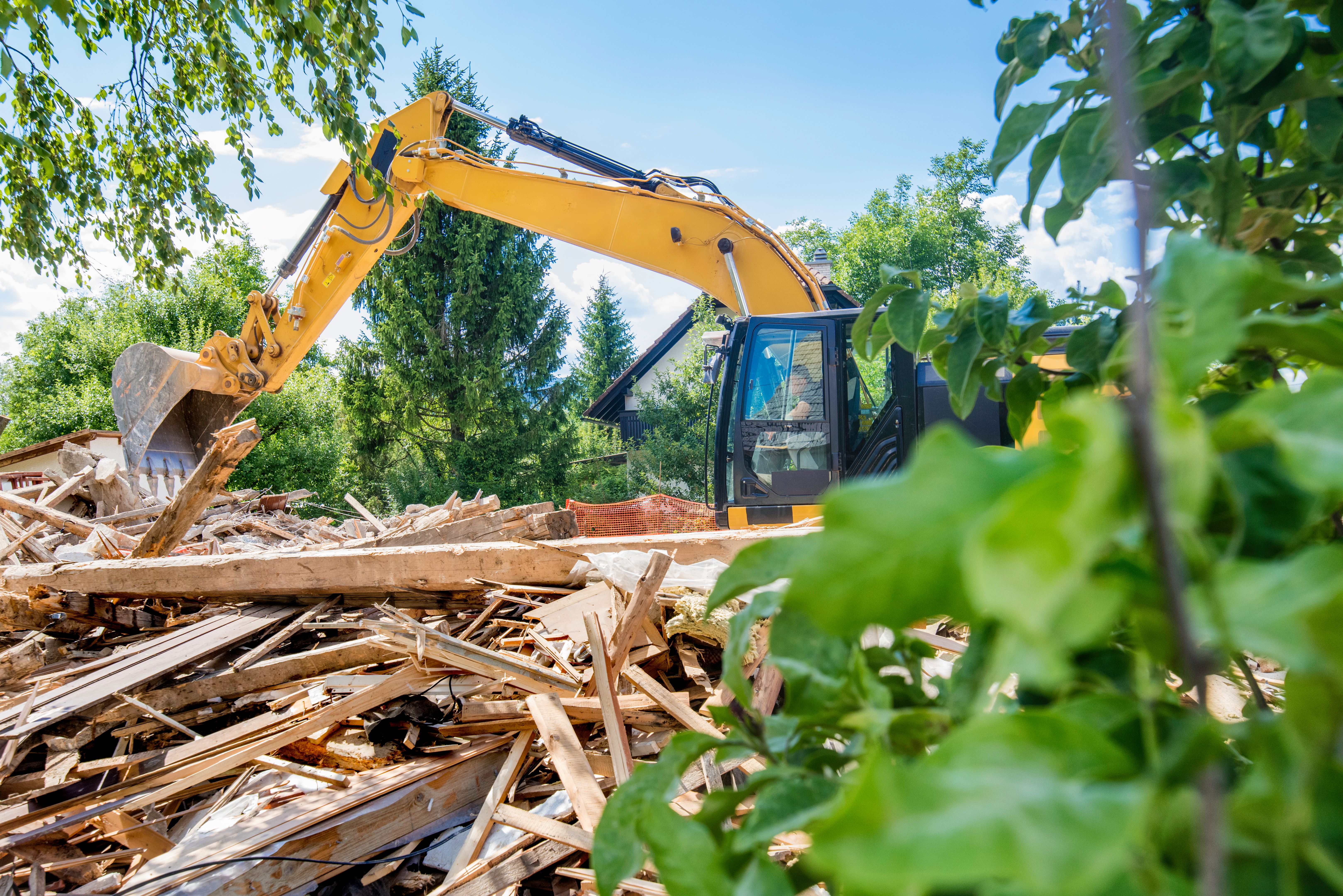 Excavator clearing rubble after demolishing a house