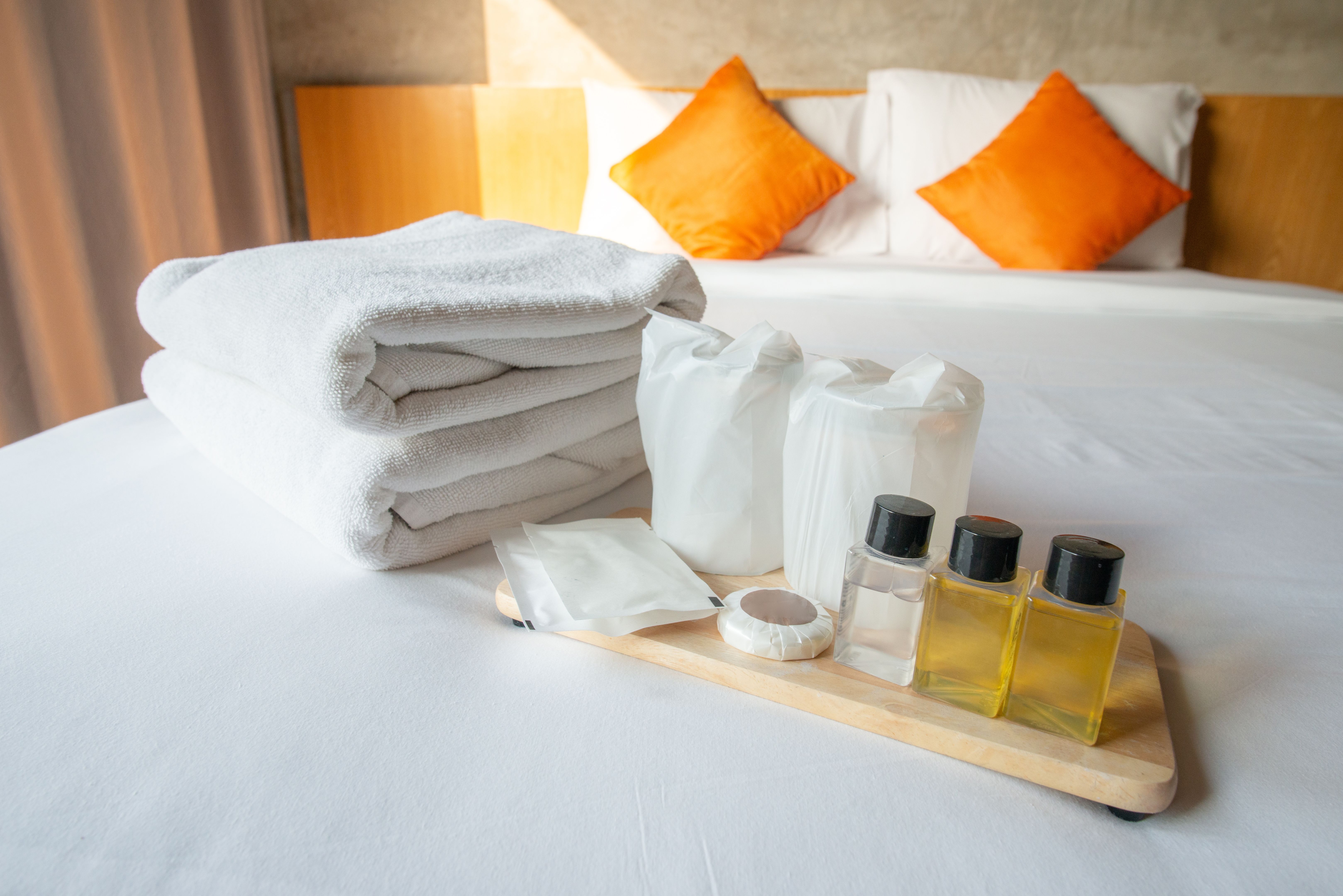 Set of hotel amenities (such as towels, shampoo, soap etc) on the bed.