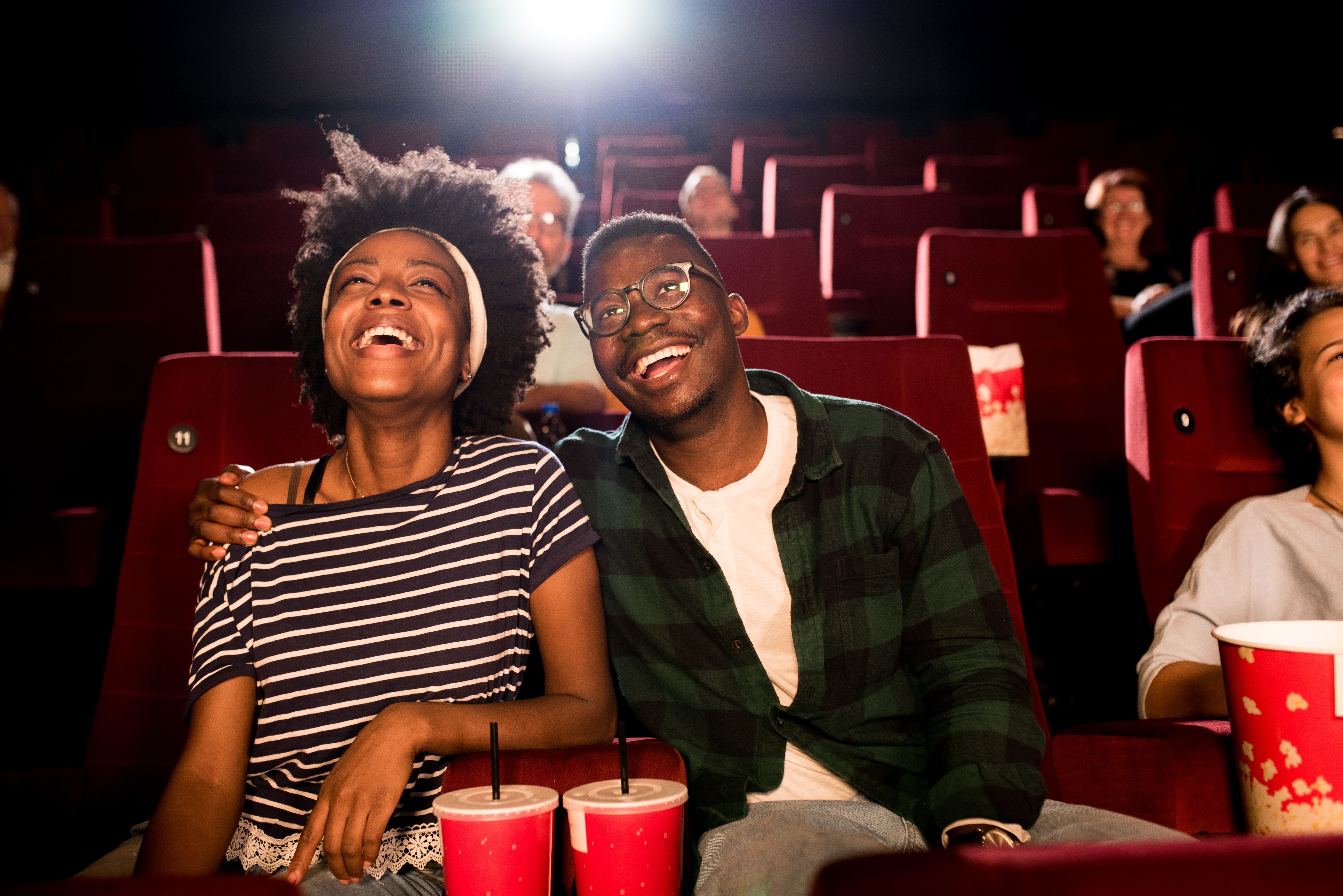 Young African-American couple watching a movie and having fun in the cinema