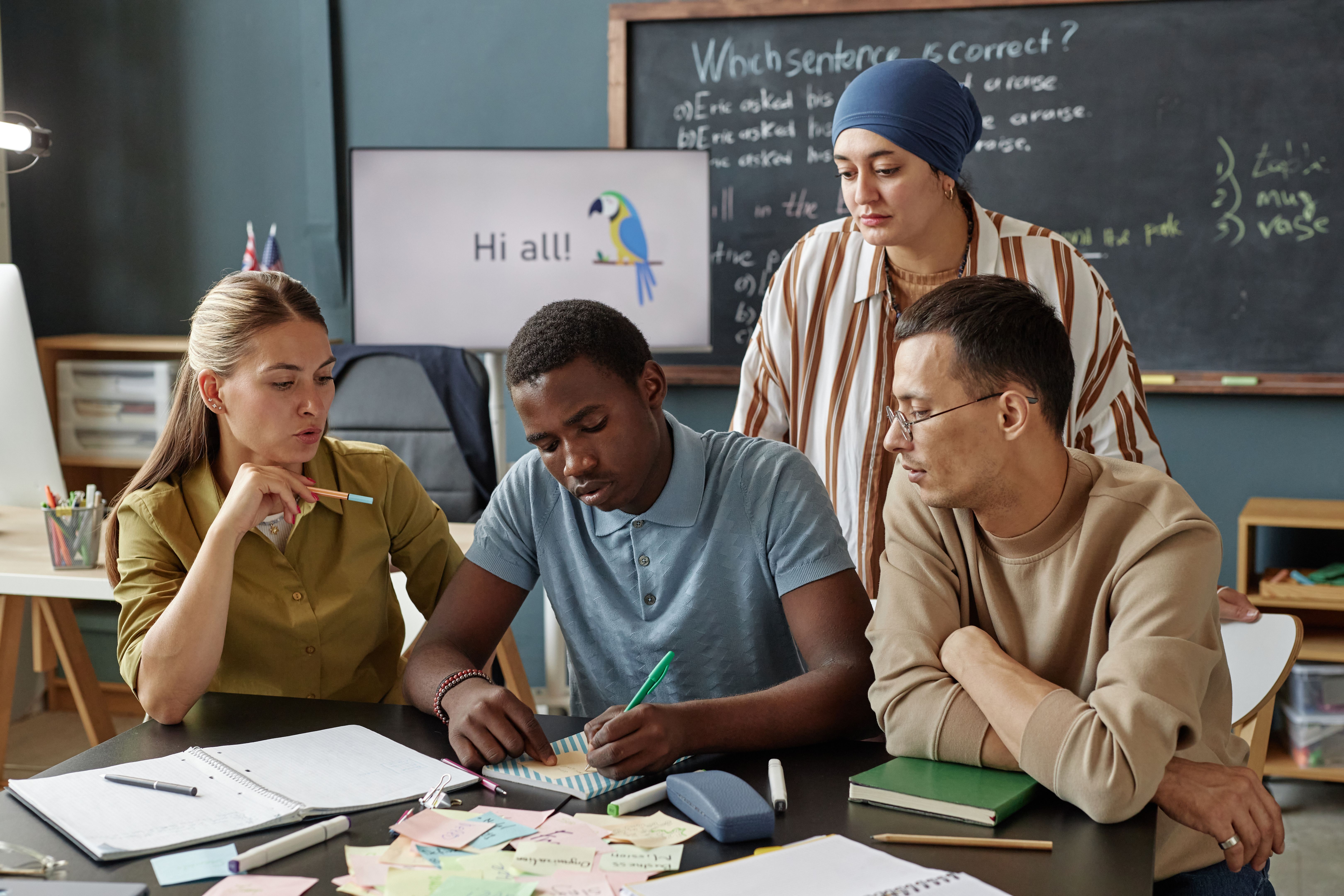 Young Black Man Writing on Sticker Studying English in Group Class at Language School