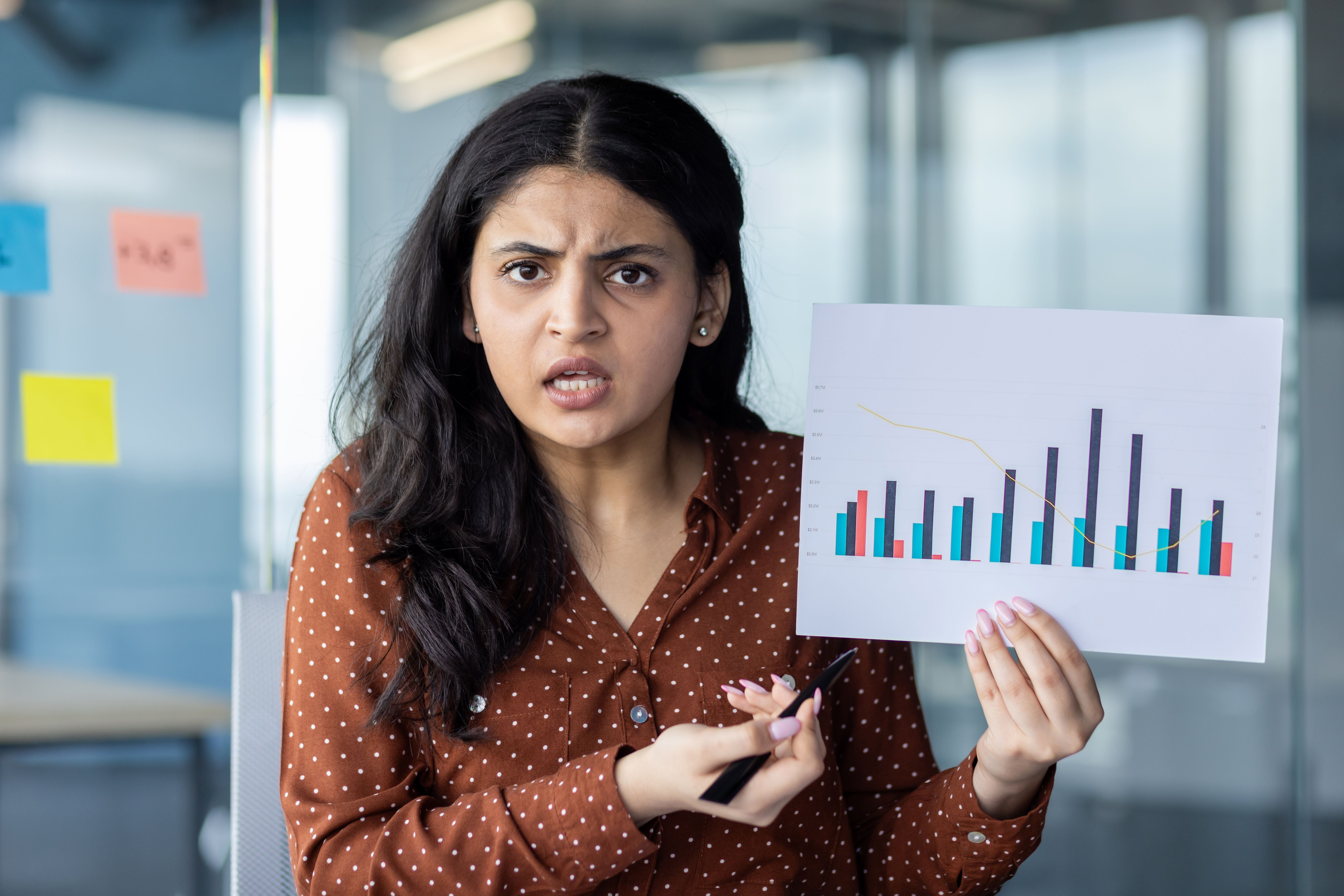 Webcam view, woman shows graph document with negative and unsatisfactory results. Businesswoman at online meeting with colleagues and partners, looking into webcam, remote conference