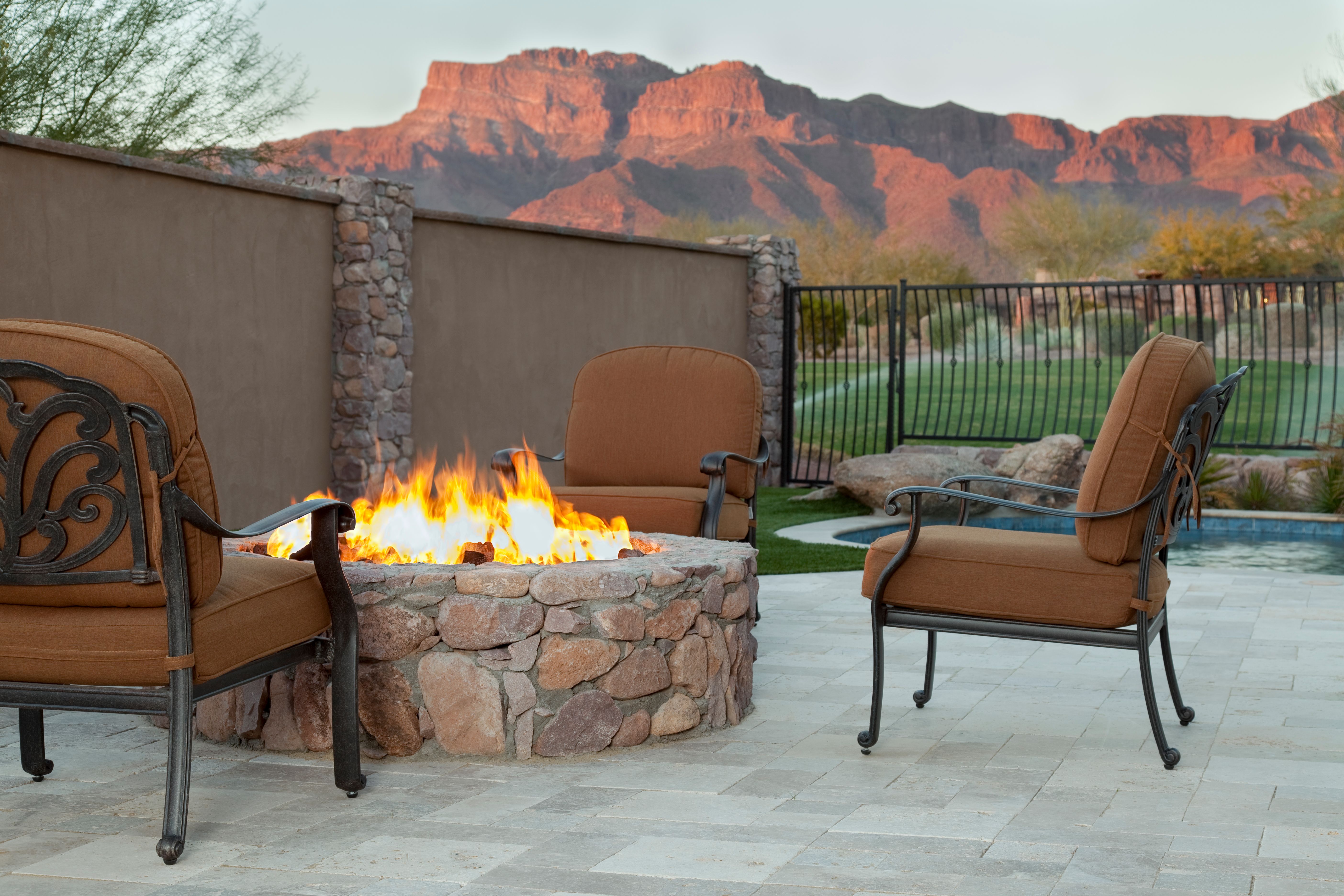 Luxury backyard fireplace next to pool on a golf course with Arizona red rock mountains in background Luxury backyard fireplace next to pool on a golf course with Arizona red rock mountains in background