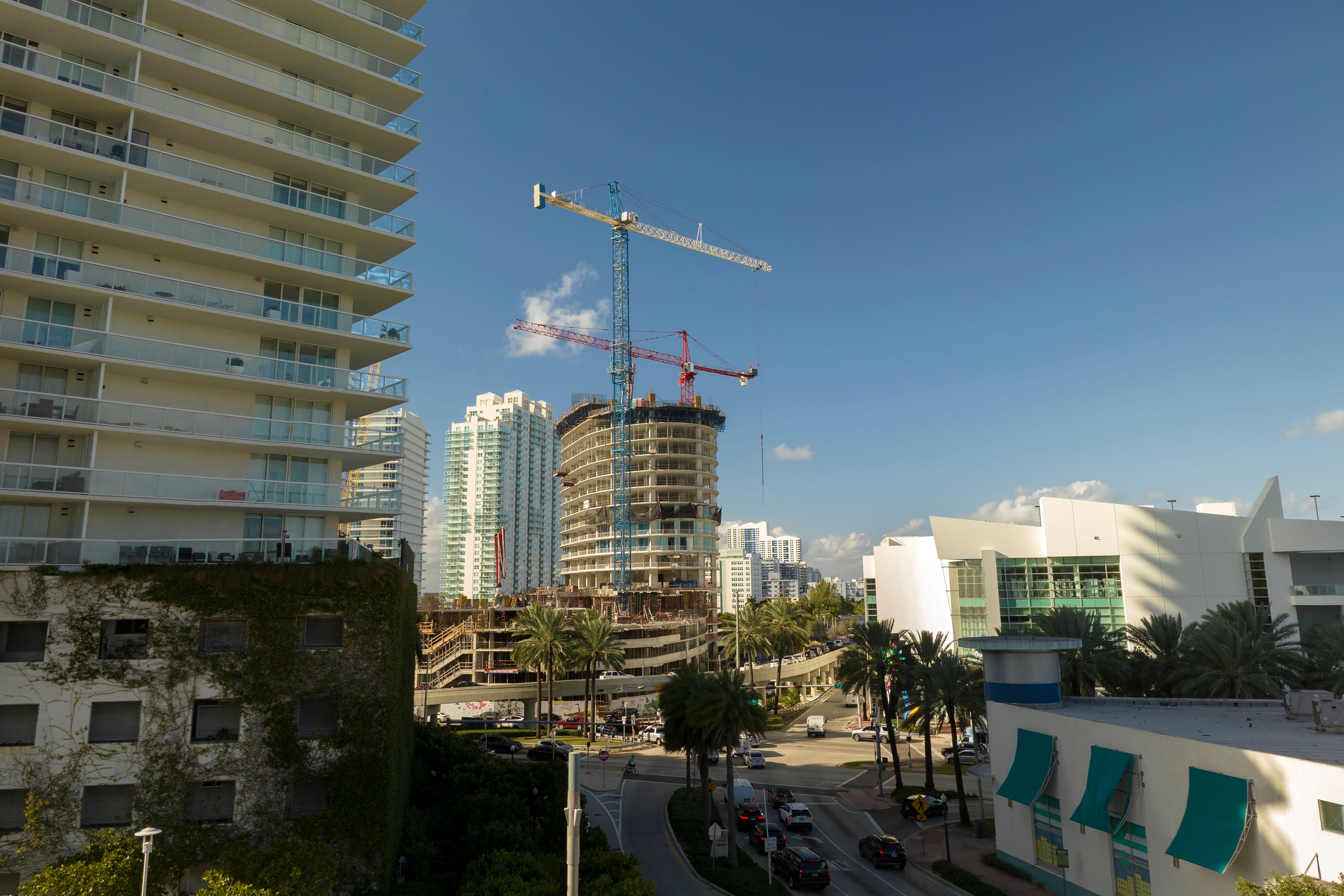 Tower lifting cranes at high residential apartment building construction site. Real estate development in Miami urban area
