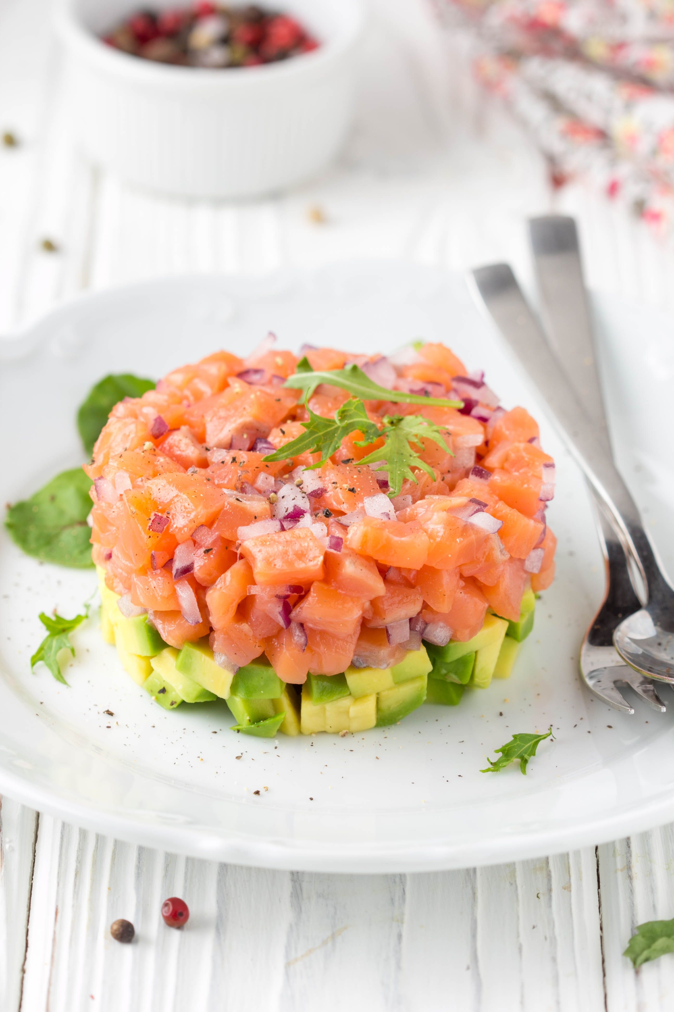 Tartare di salmone con cipolla rossa, avocado, rucola, pane tostato. Bellissimo spuntino, cibo dietetico, antipasto per le vacanze di Natale. Su sfondo bianco in legno Tartare di salmone con cipolla rossa, avocado, rucola, pane tostato. Bellissimo spuntino, cibo dietetico, antipasto per le vacanze di Natale. Su sfondo bianco in legno