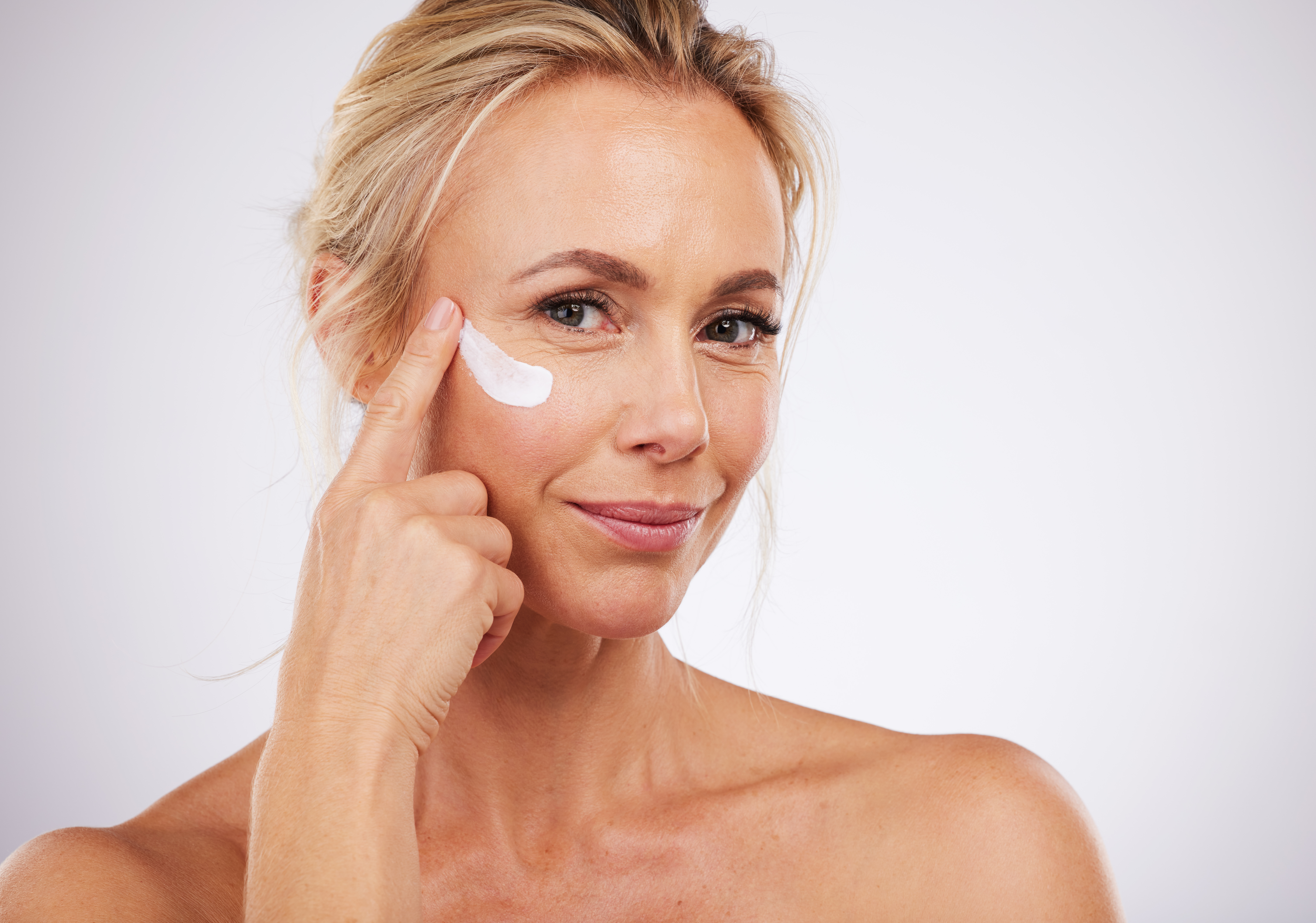 Portrait, face cream and skincare for mature woman in studio for wellness, beauty and care on grey background. Facial, product or sunscreen by lady relax in luxury, cosmetic and lotion while isolated Portrait, face cream and skincare for mature woman in studio for wellness, beauty and care on grey background. Facial, product or sunscreen by lady relax in luxury, cosmetic and lotion while isolated
