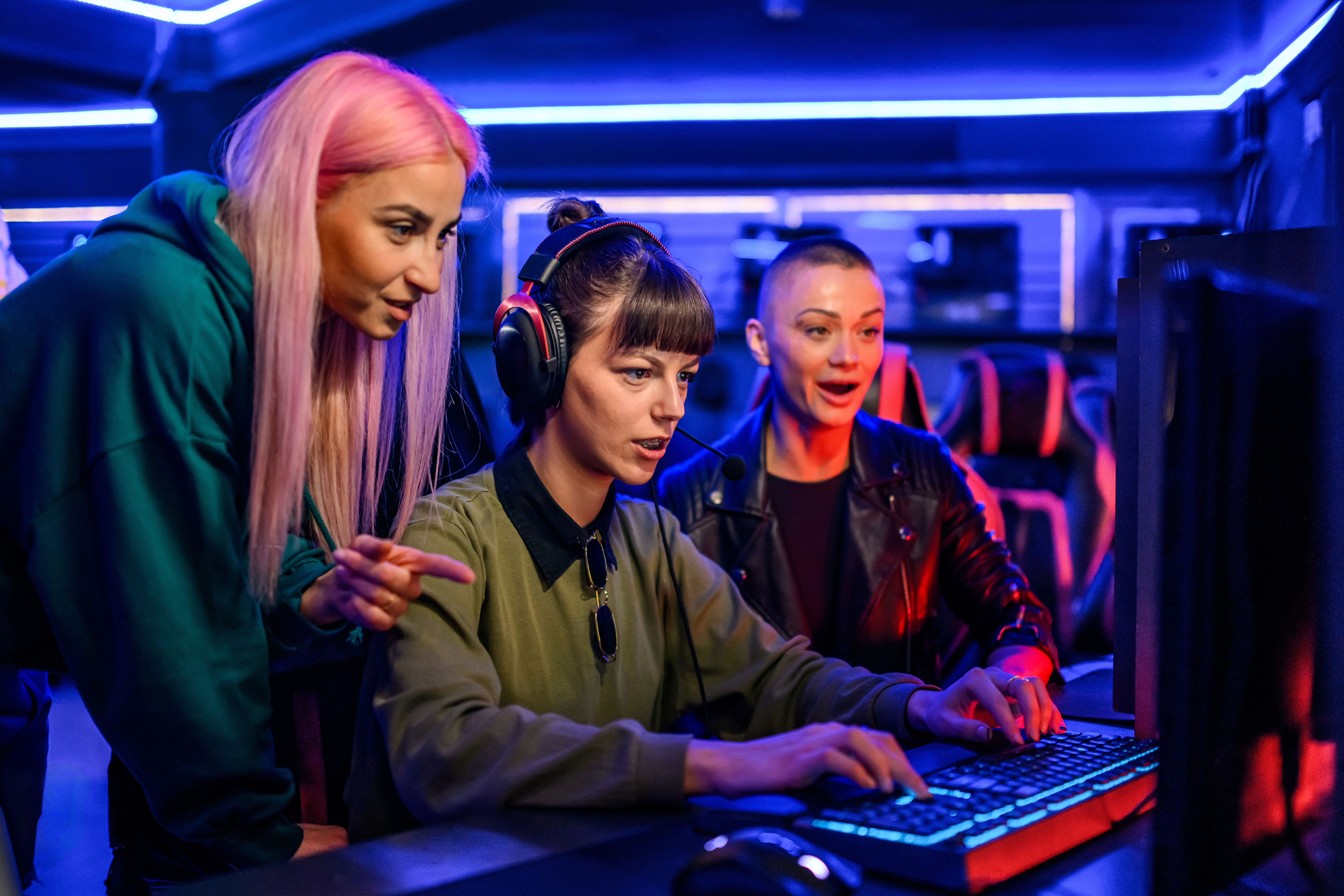 Portrait of a three woman gamers playing video games in internet cafe