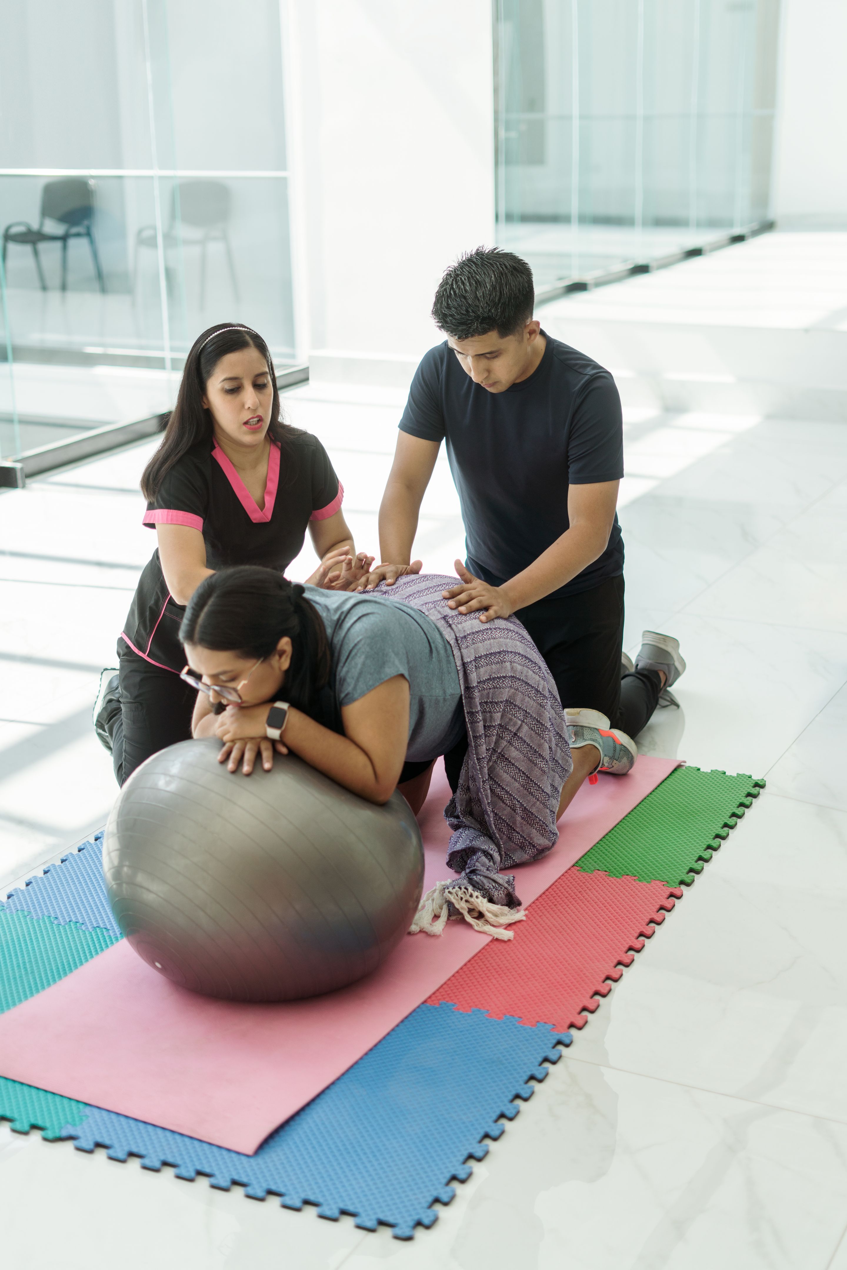 Instructor explains to young man how to help with exercises that provide comfort to his pregnant wife