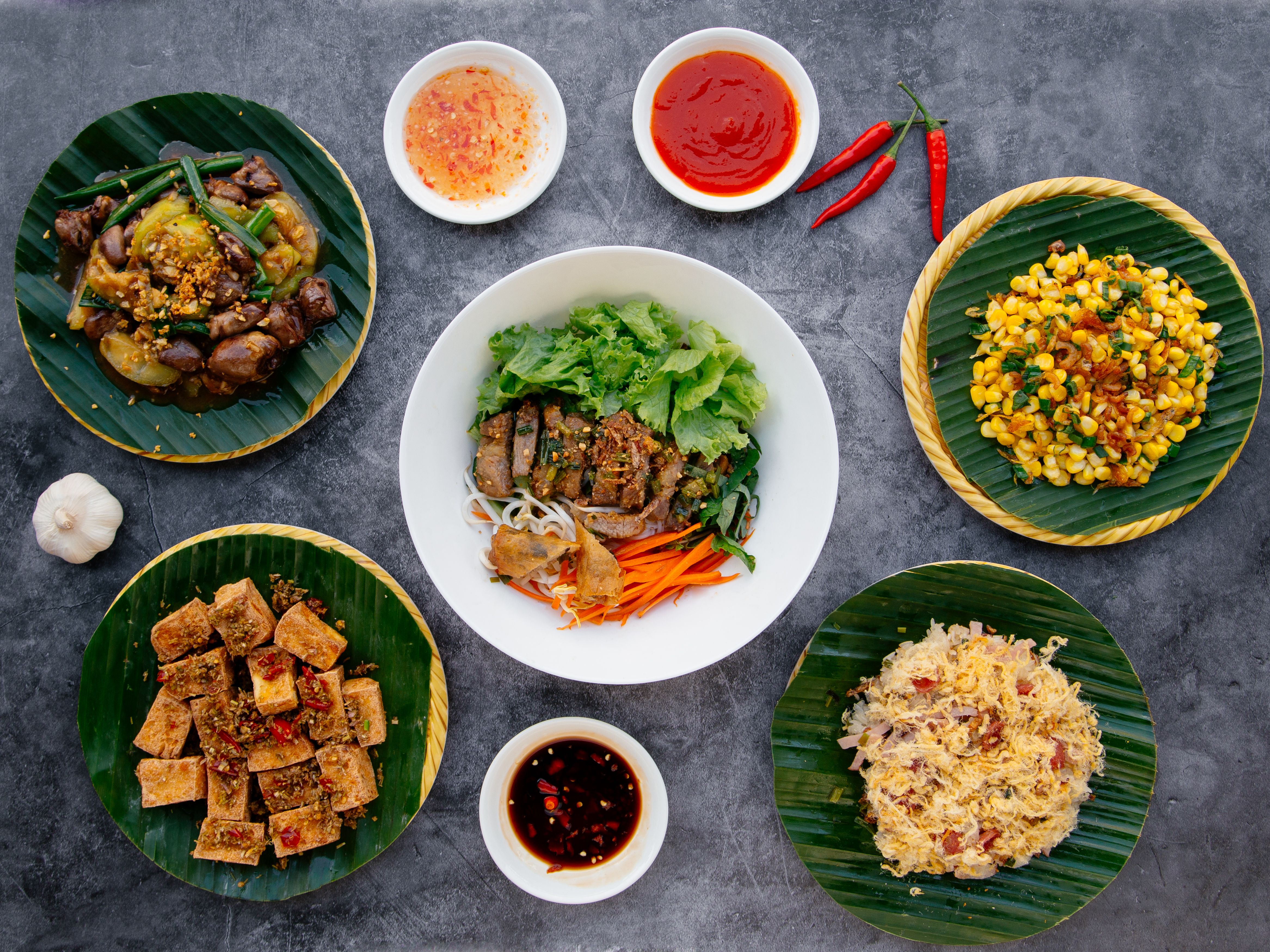 Viet Sea Tofu With Lemongrass, Mixed Sticky Rice noodle, Chicken Heart And Lungs, Fried Corn, Deep Fried Pig Intestine salad served in bowl isolated on dark grey background top view of japanese food