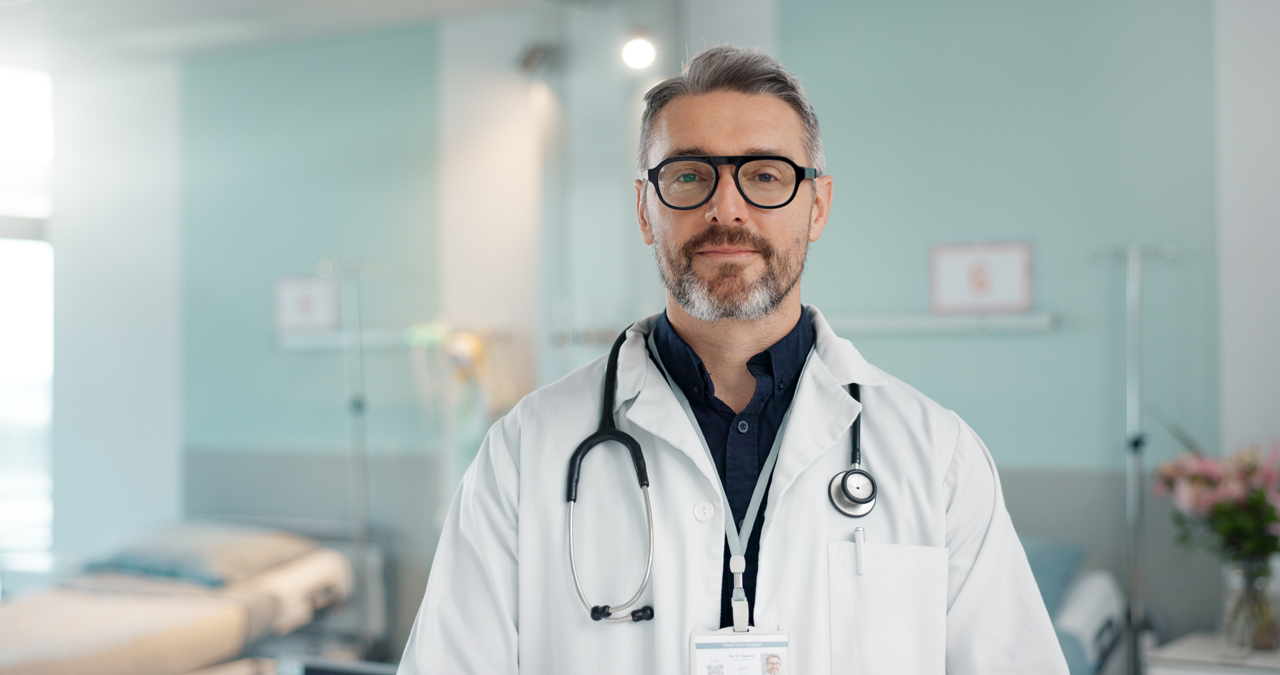 Healthcare, doctor and man with arms crossed at hospital with smile for support, service and wellness. Medicine, professional and expert with glasses and pride for career, surgery, insurance and care