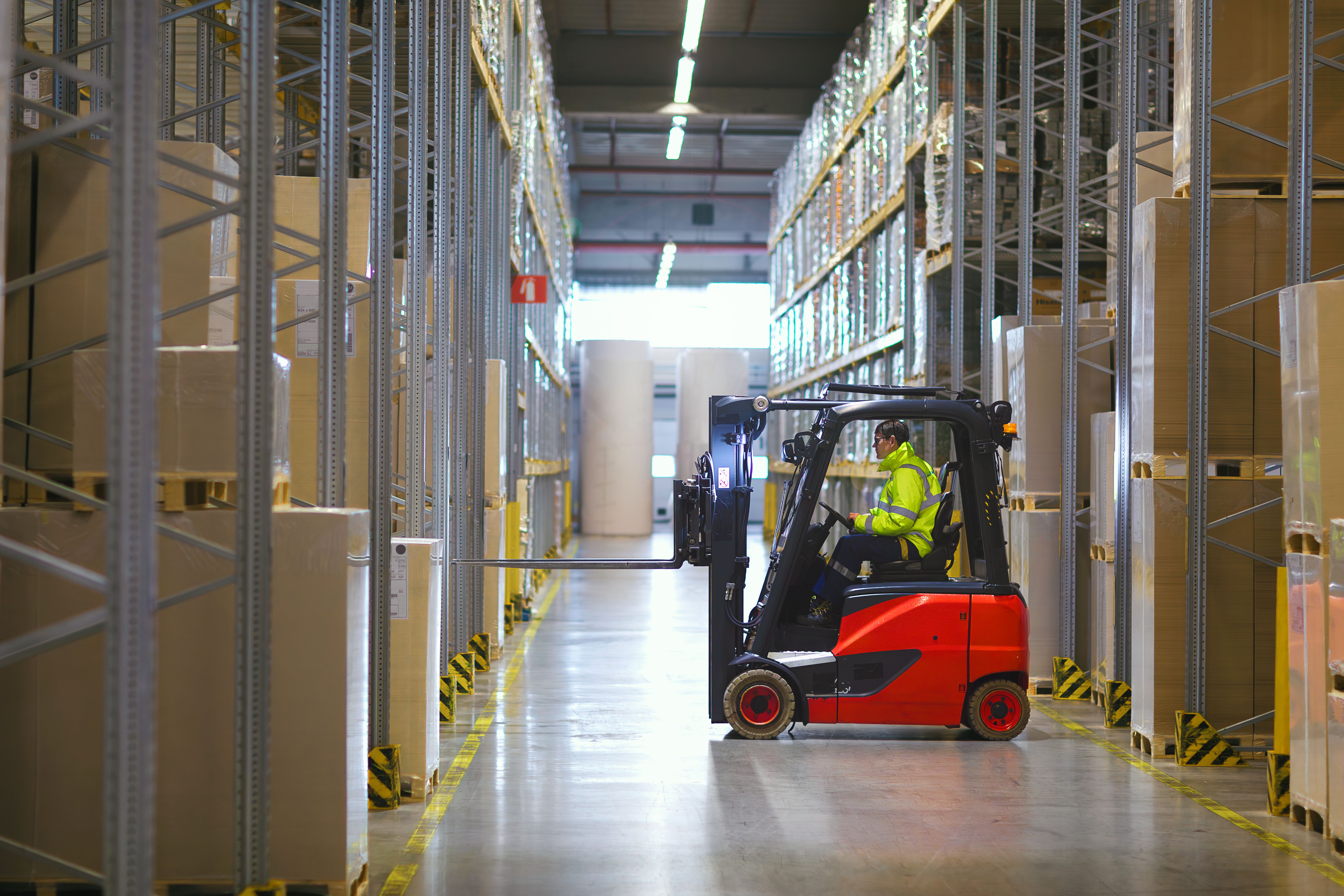 Warehouse worker moving inventory using fork-lift.