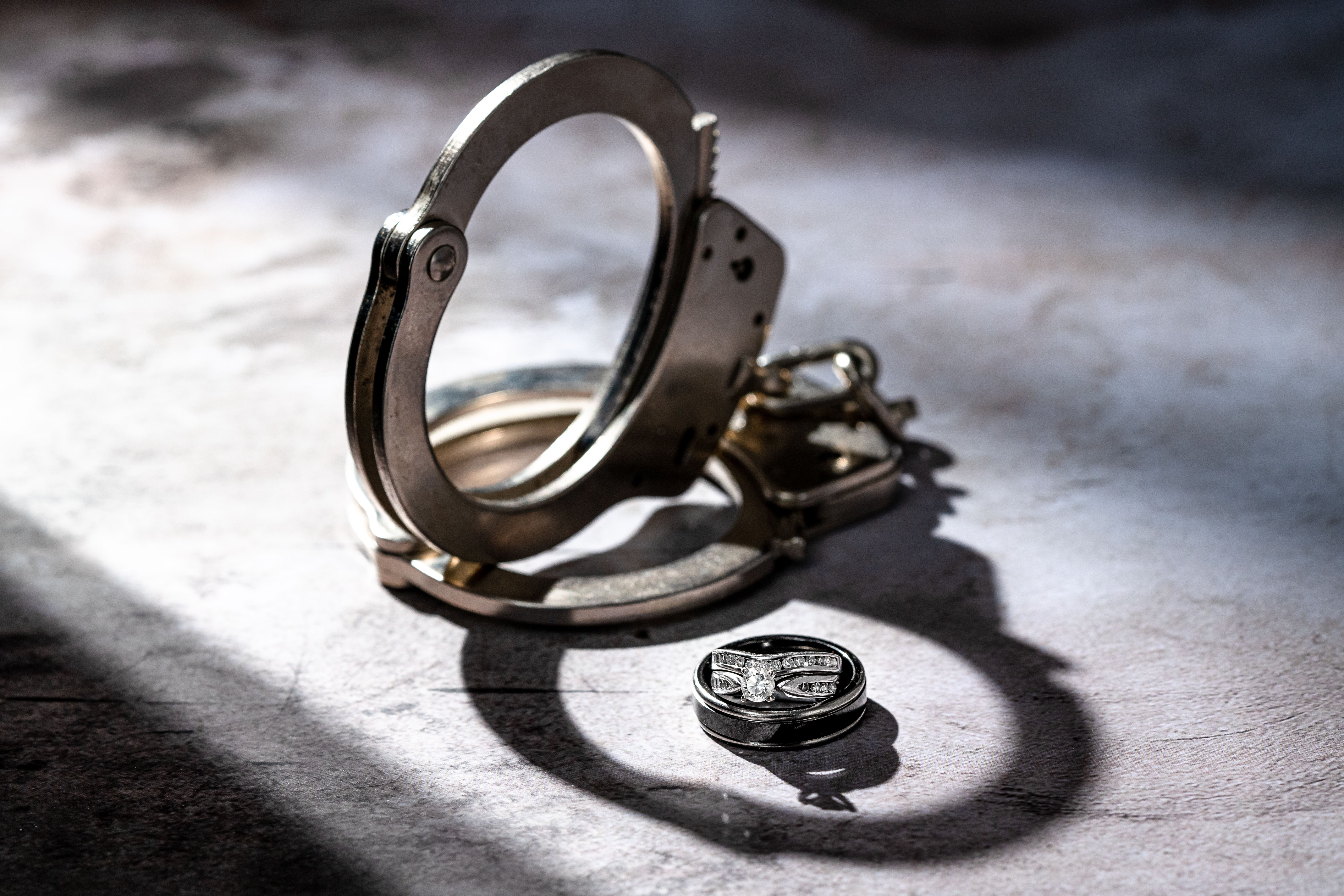 Handcuffs in Shadow Light with Diamond Wedding Rings and possible Jail for Domestic Violence