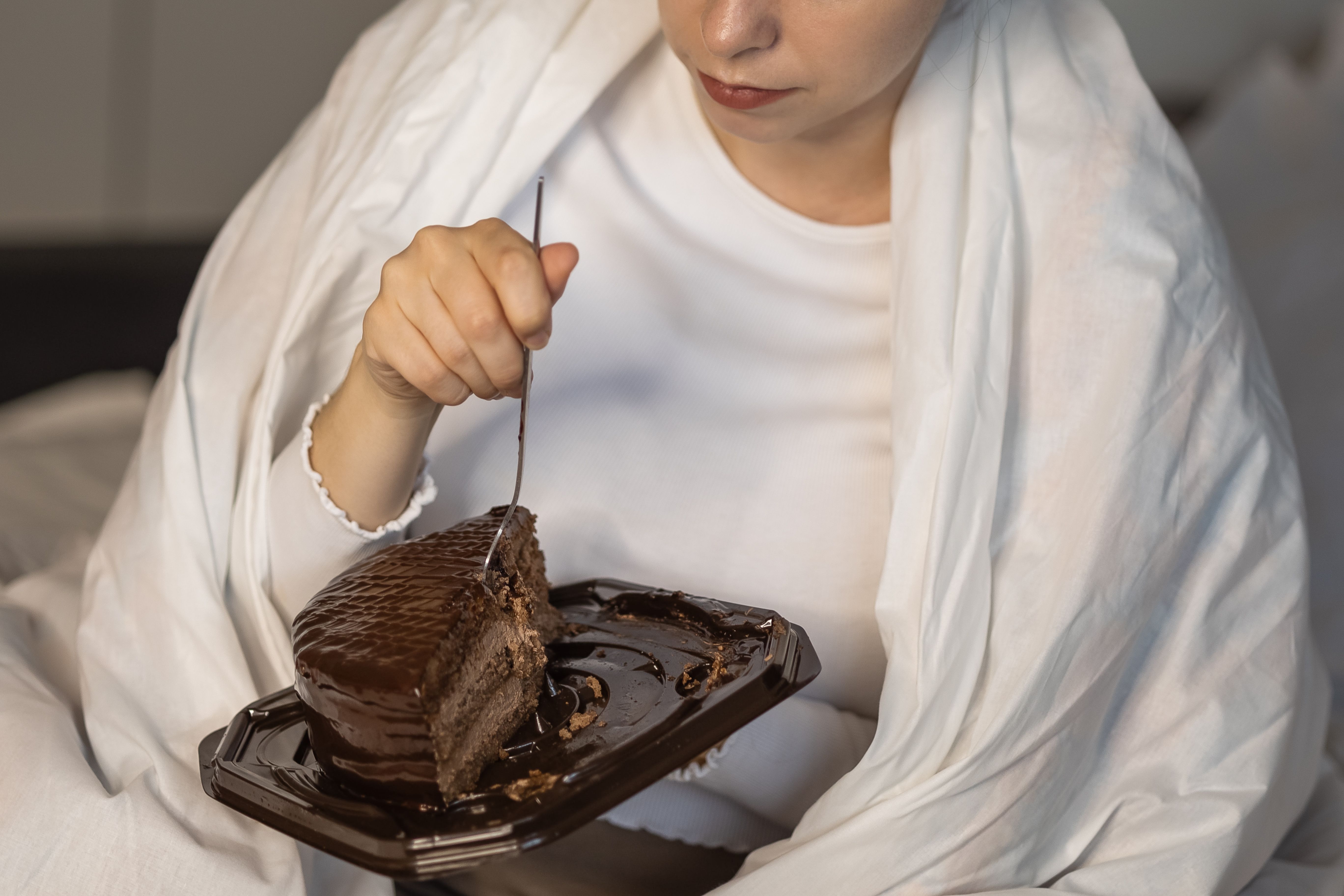 Enjoying chocolate cake while wrapped in a cozy blanket during a relaxing evening at home