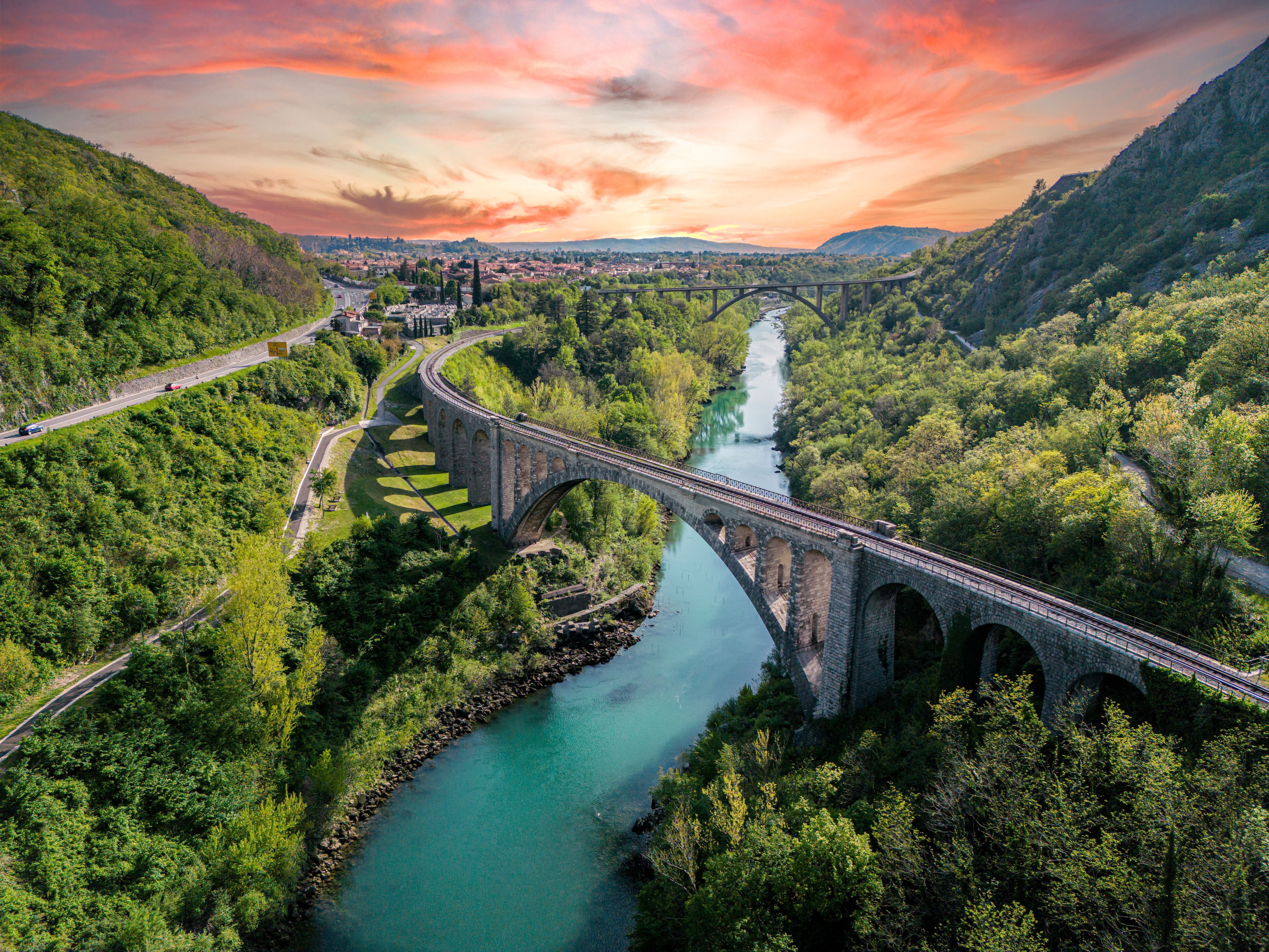 Amazing sunset view of a large stone railway bridge over beautiful green Soca river, aerial view in Slovenia