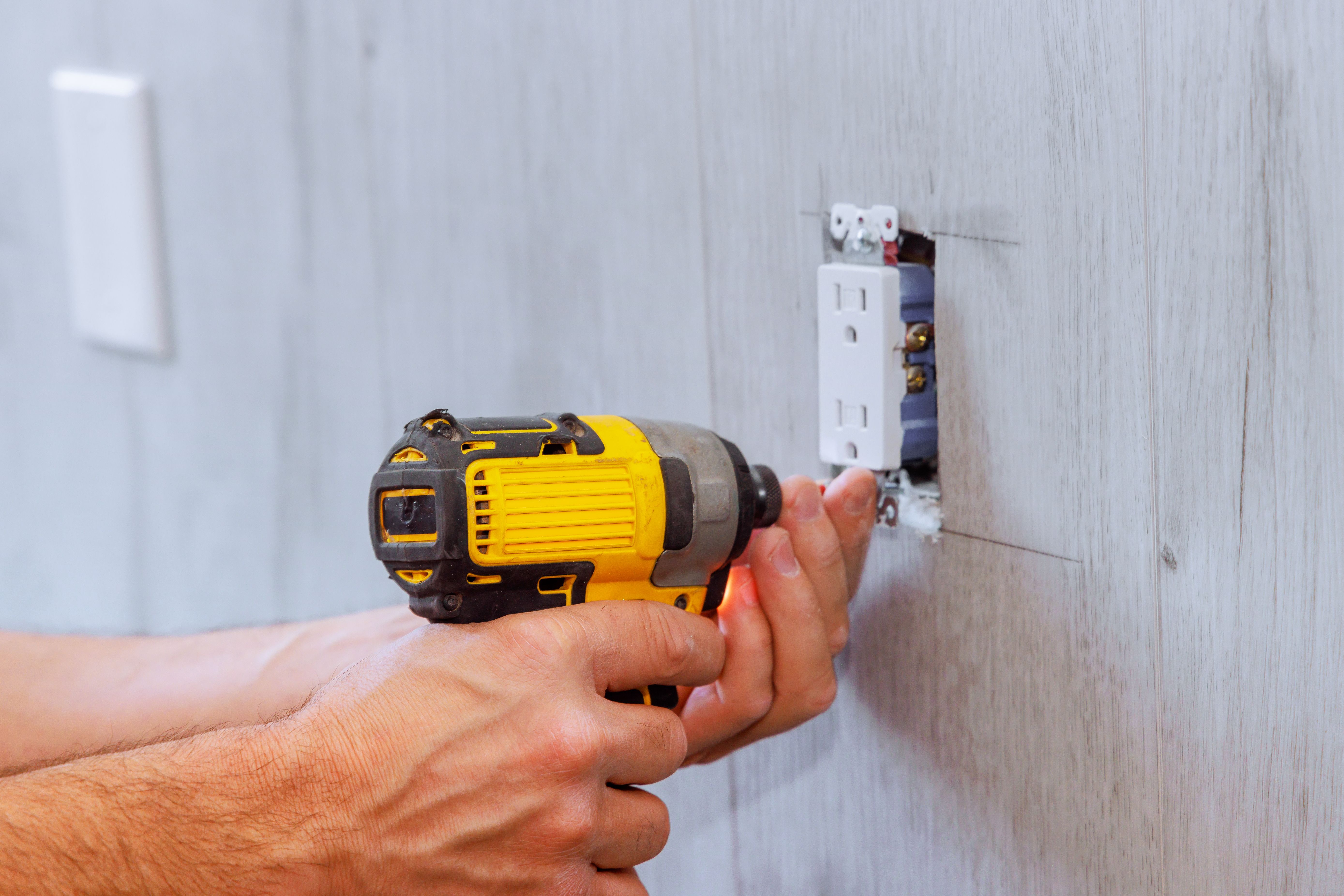 During reconstruction of house, electrician installs an outlet using a screwdriver