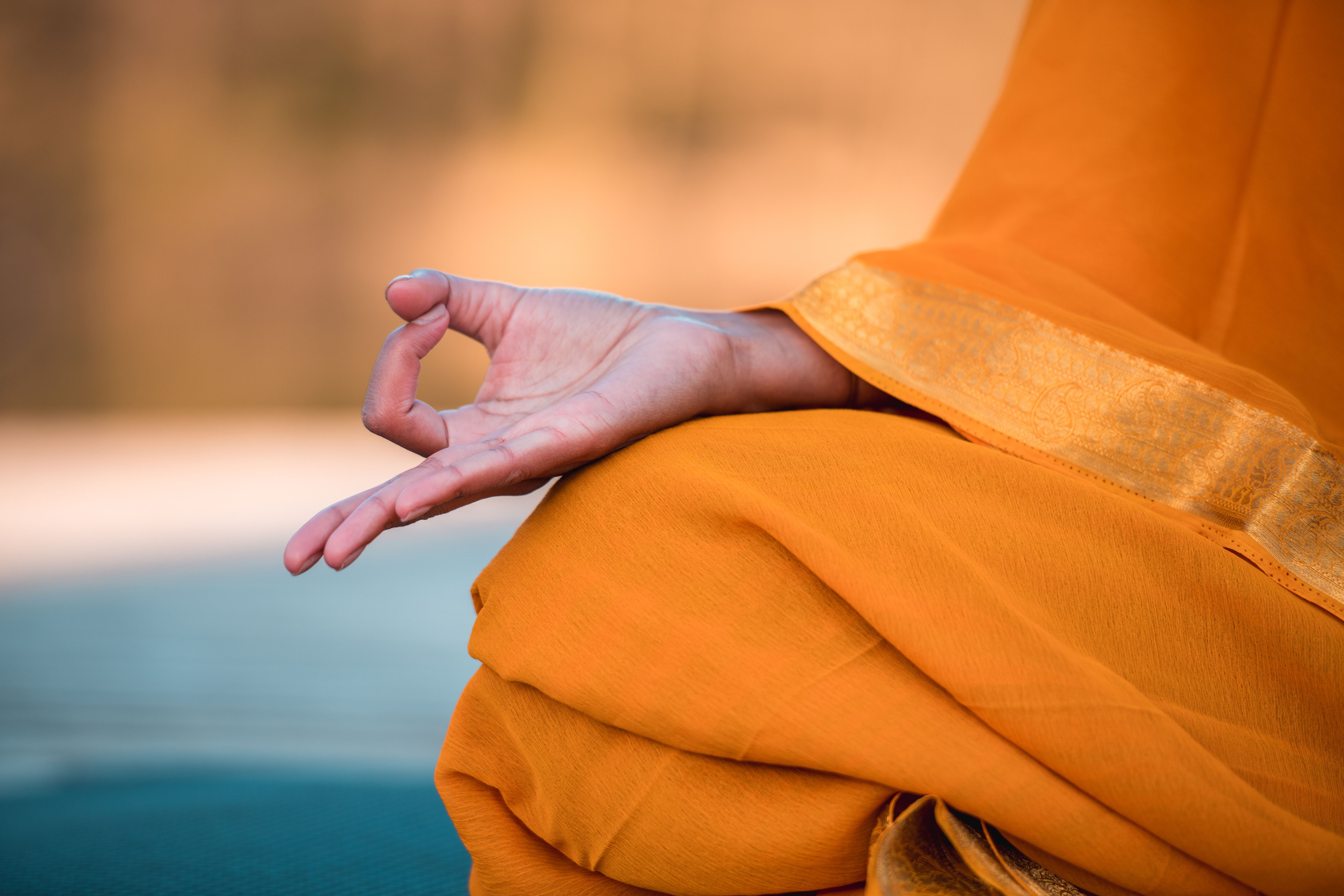 Female Hand in Lotus Position on Orange Fabric Female Hand in Lotus Position on Orange Fabric
