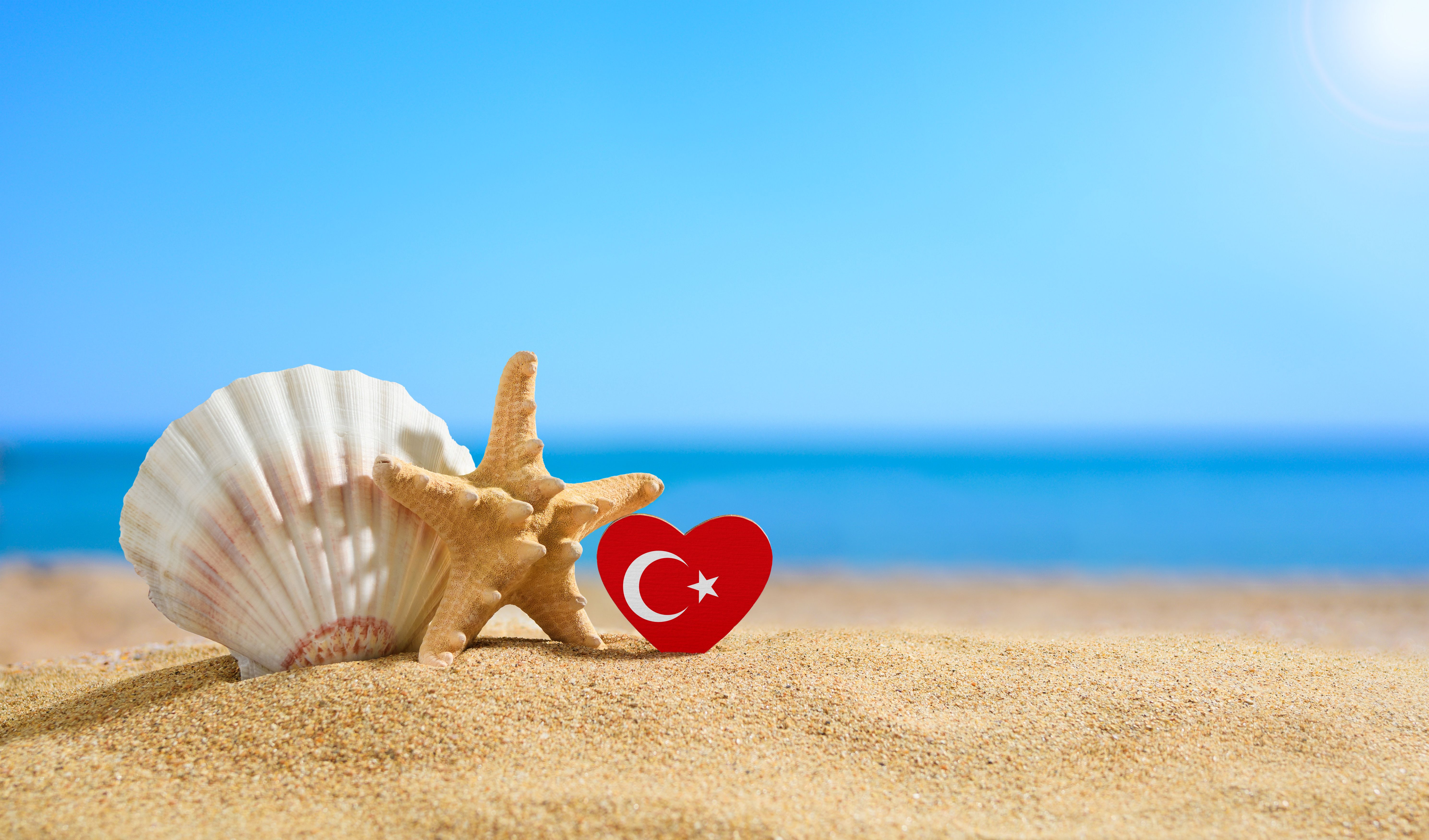 Beautiful beach in Turkey. Flag of Turkey in the shape of a heart and shells on a sandy beach.