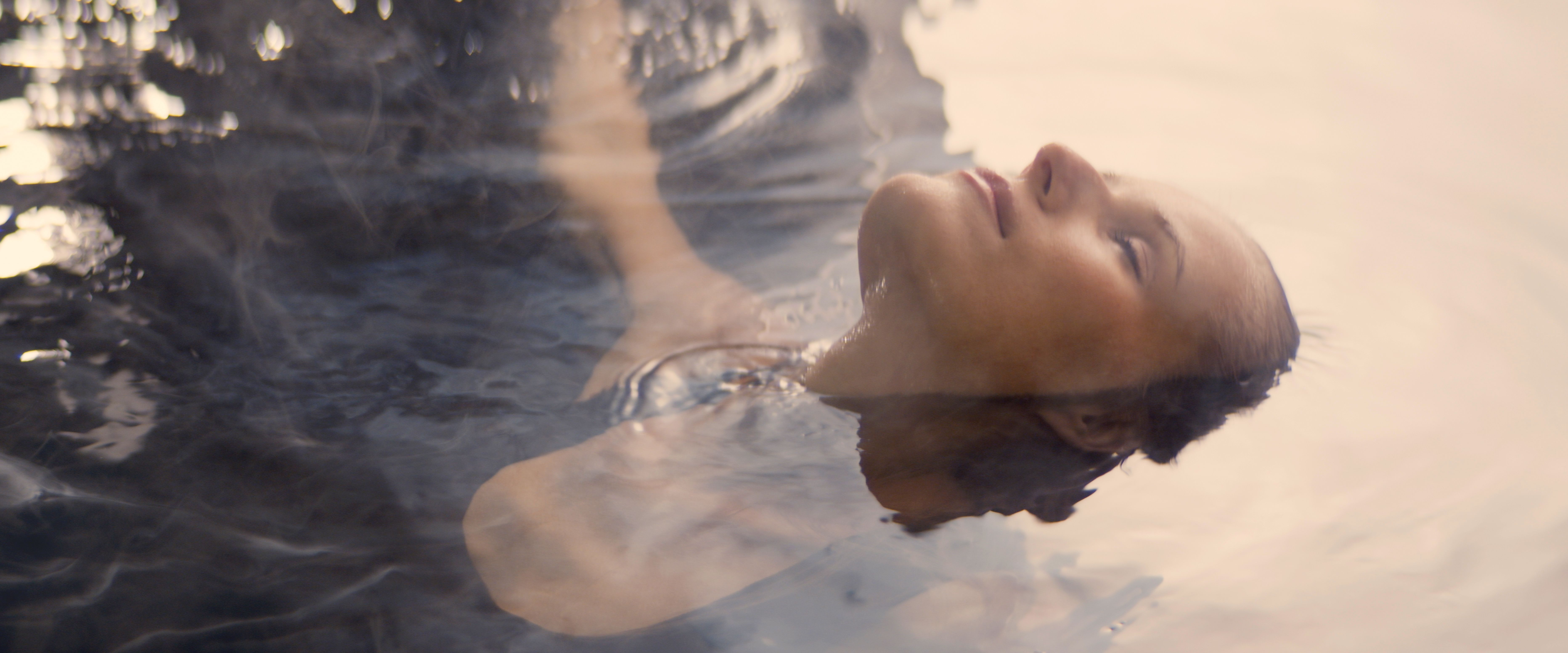 Delicate woman emerging from dark water. Natural beauty care metaphor