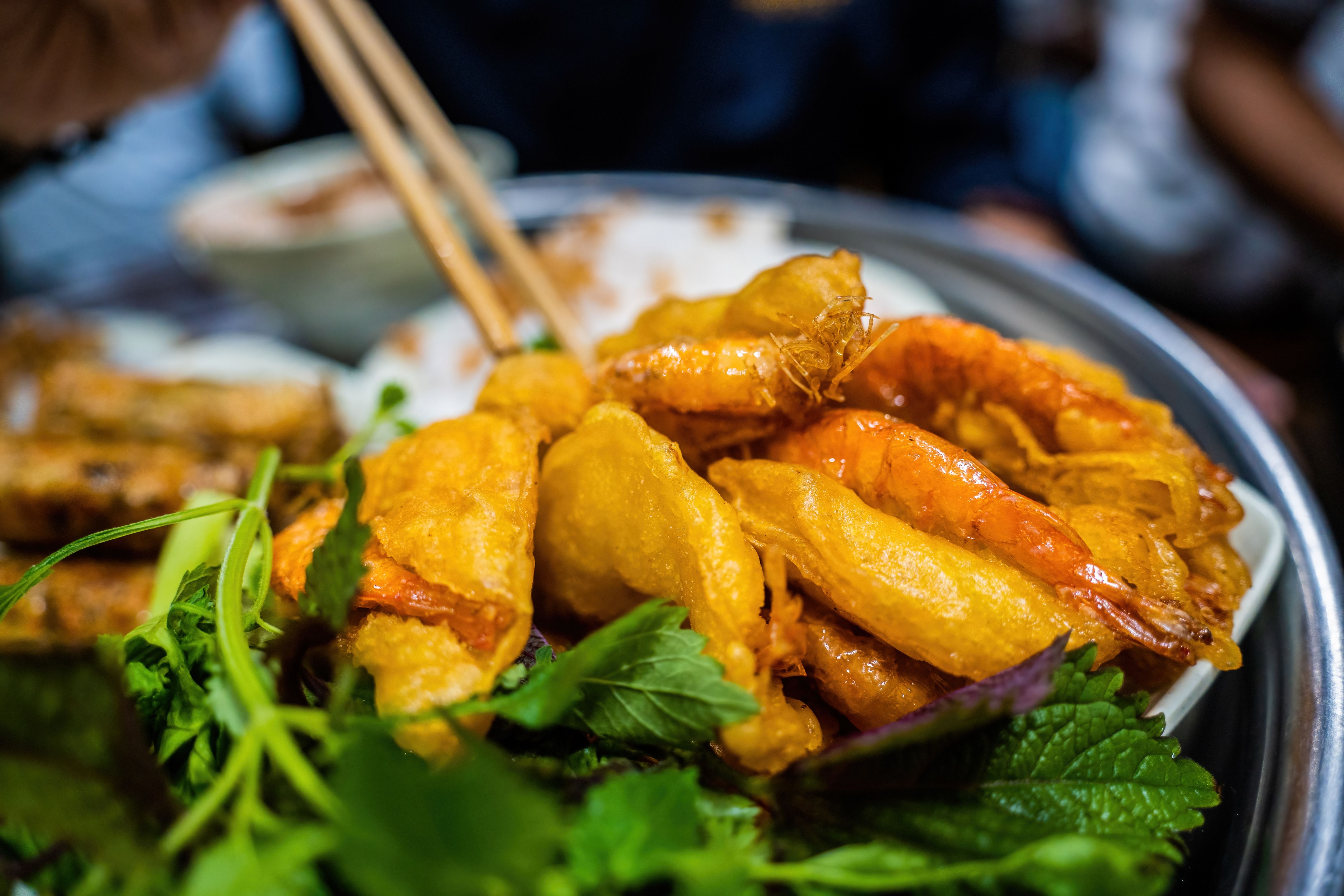 Banh cuon - Vietnamese steamed rice rolls with minced meat inside accompanied by bowl of fish sauce. Detail.