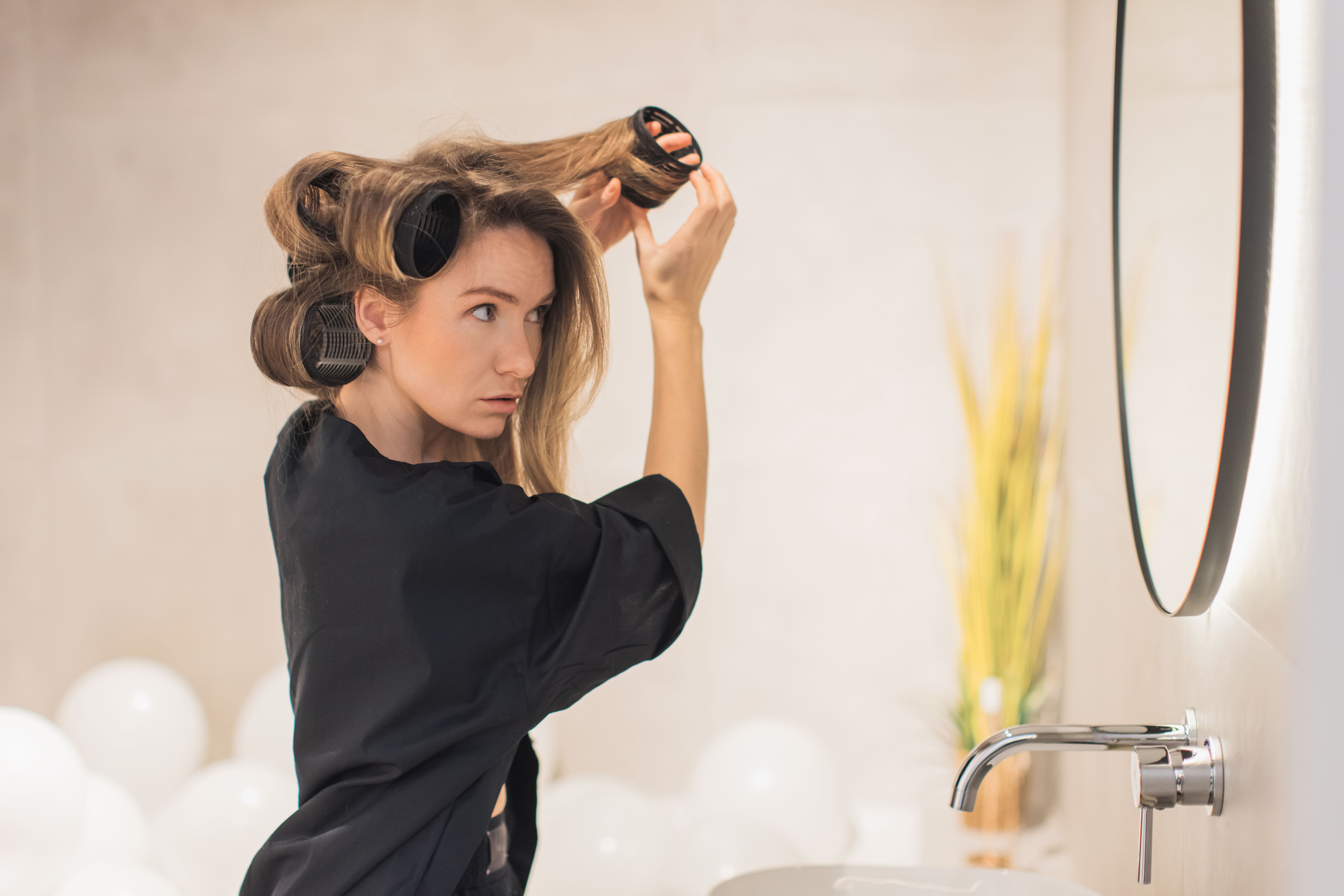 Woman twirls hair. Curlers