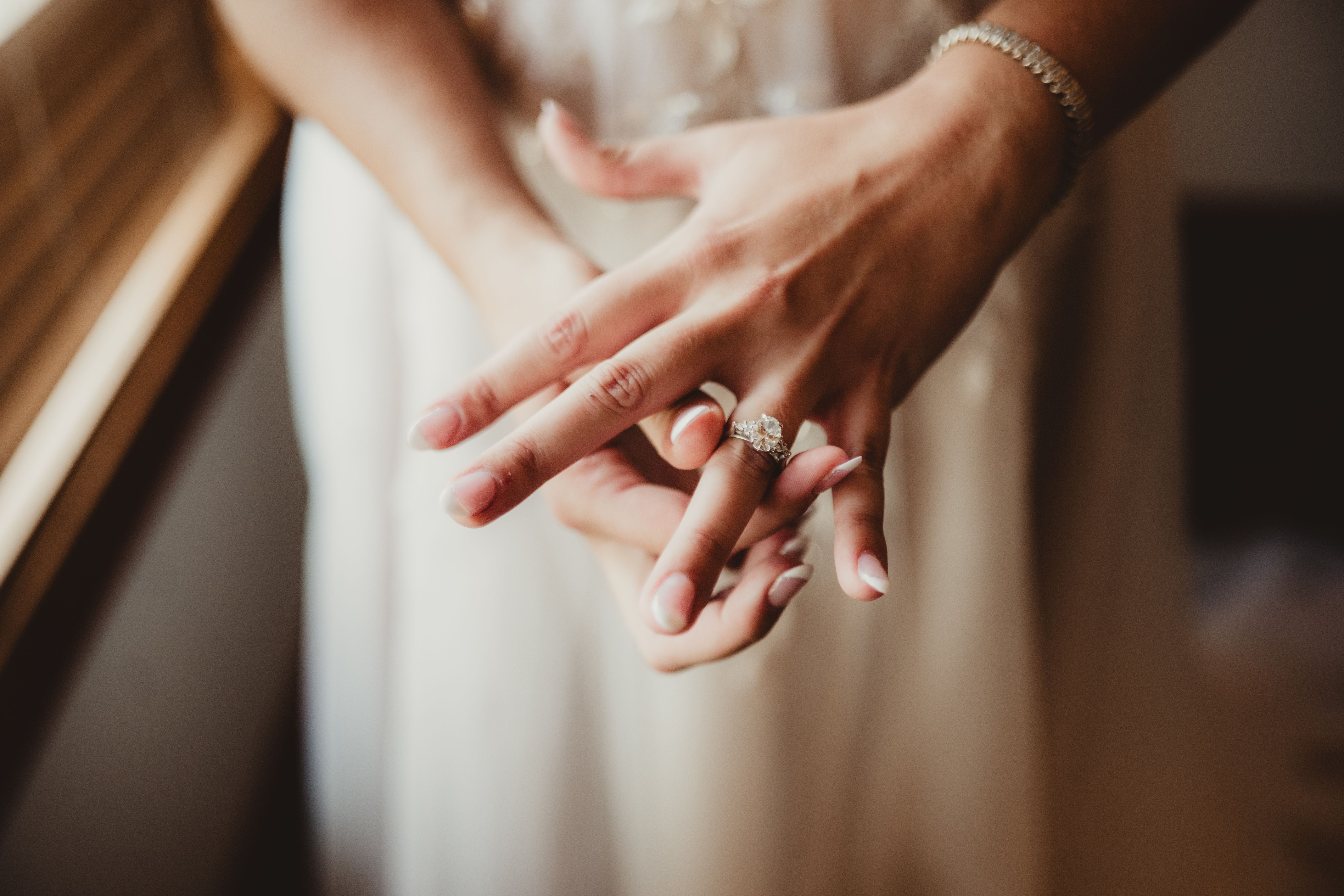 Woman in wedding dress putting on engagement ring
